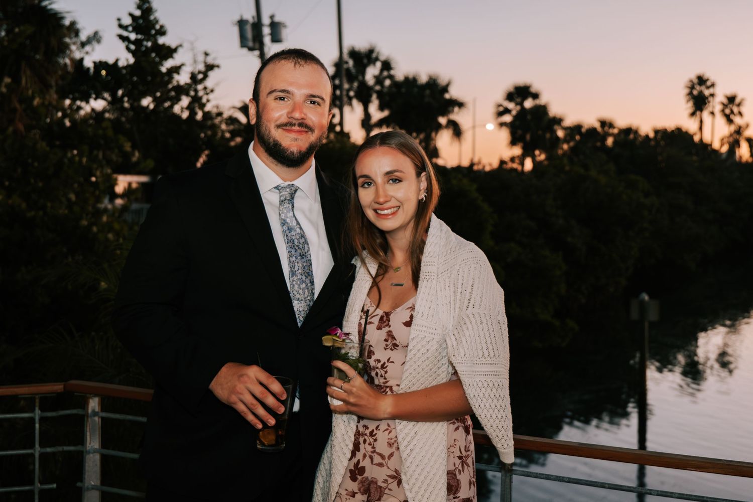 Wedding celebration at sunset with palm trees and string lights creating a romantic atmosphere.