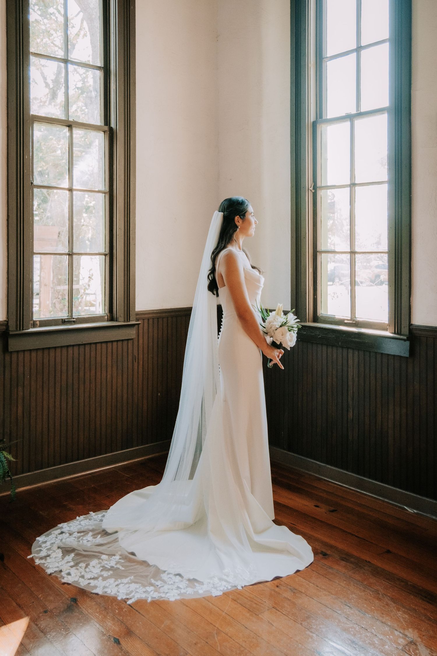 Elegant bridal portraits in sunlit room with dark wood trim and hardwood floors.