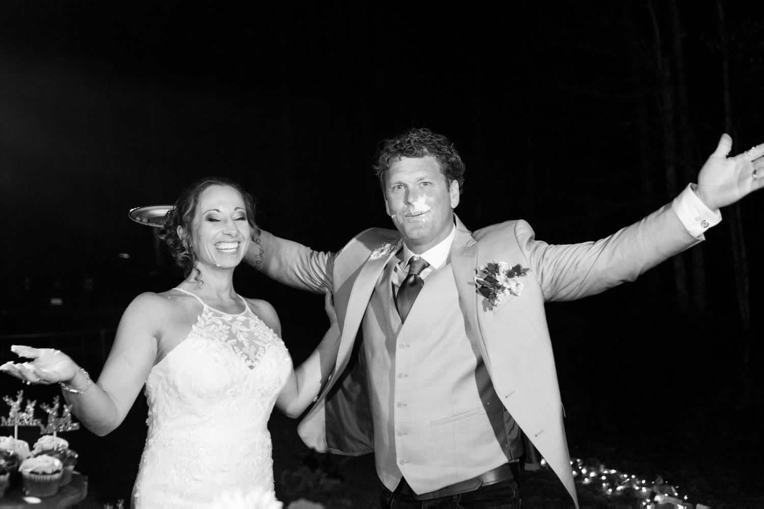 Black and white photo of smiling bride and groom celebrating at their wedding reception.