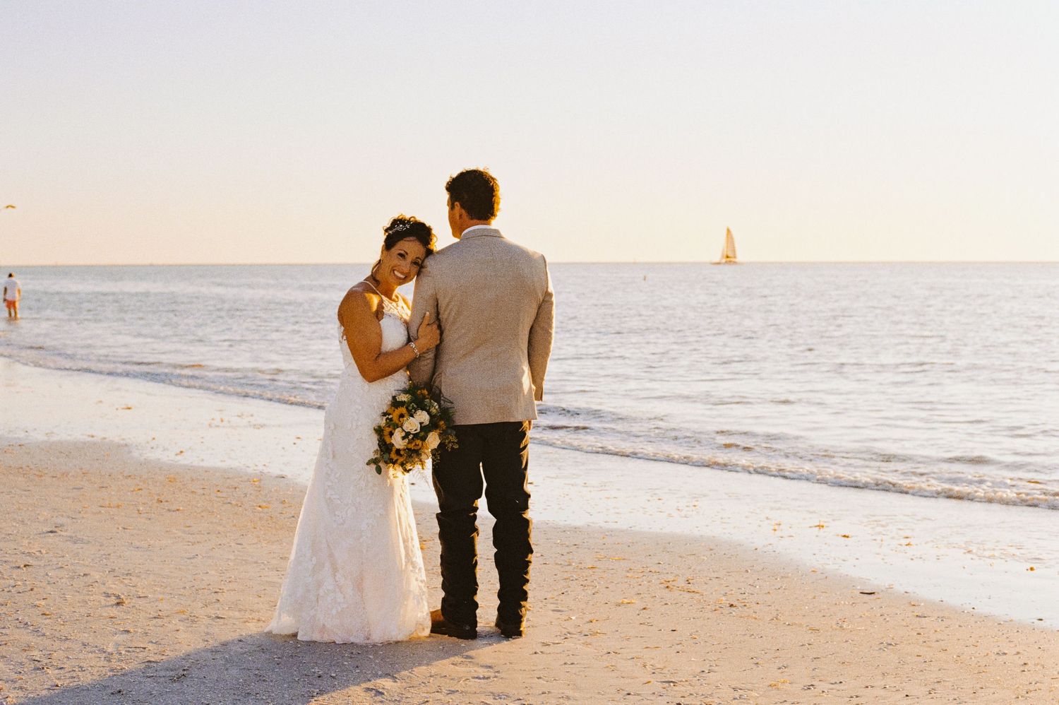 Bride and groom standing together at sunset on a beautiful sandy beach.
