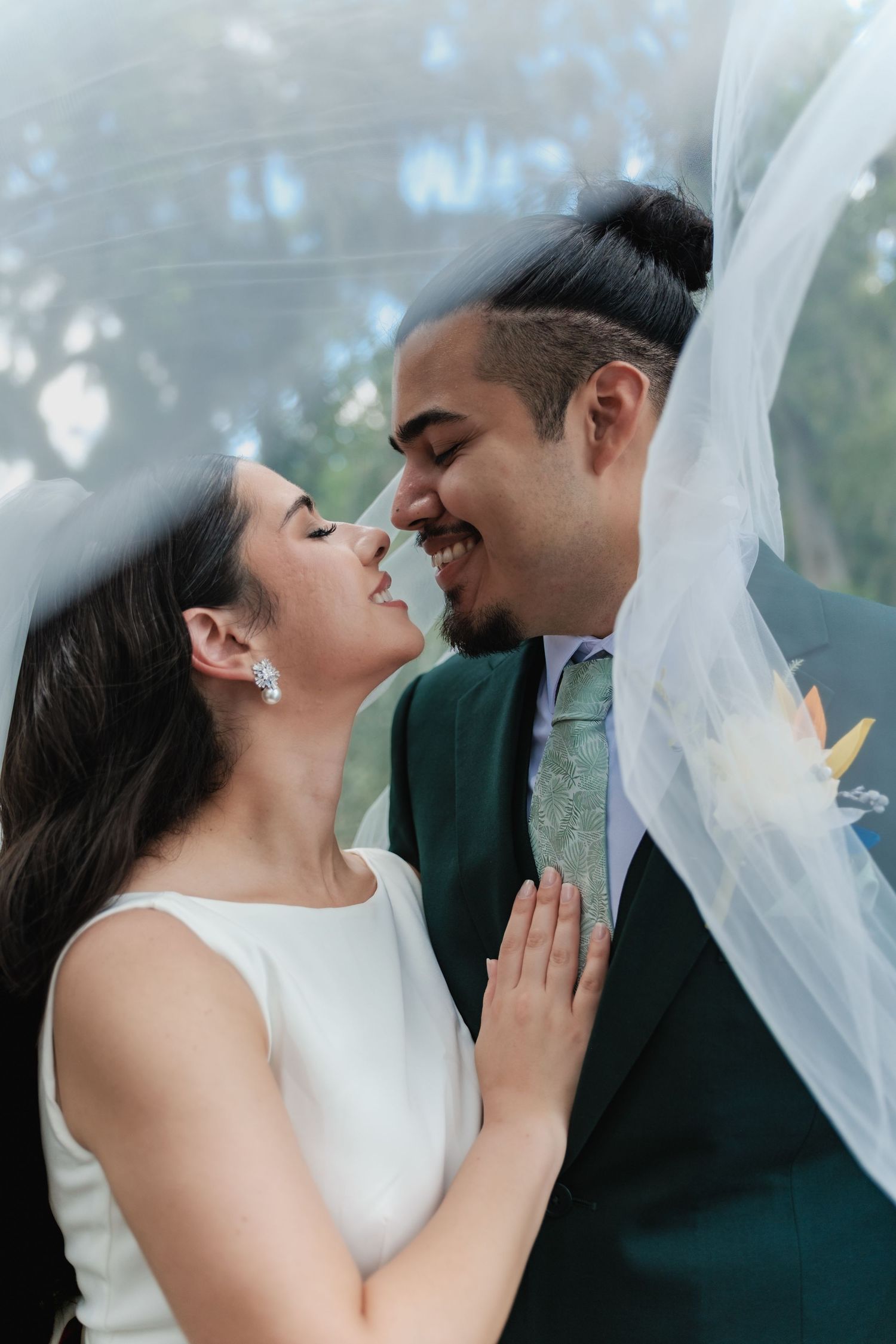 Romantic moment between newlyweds under flowing white veil.
