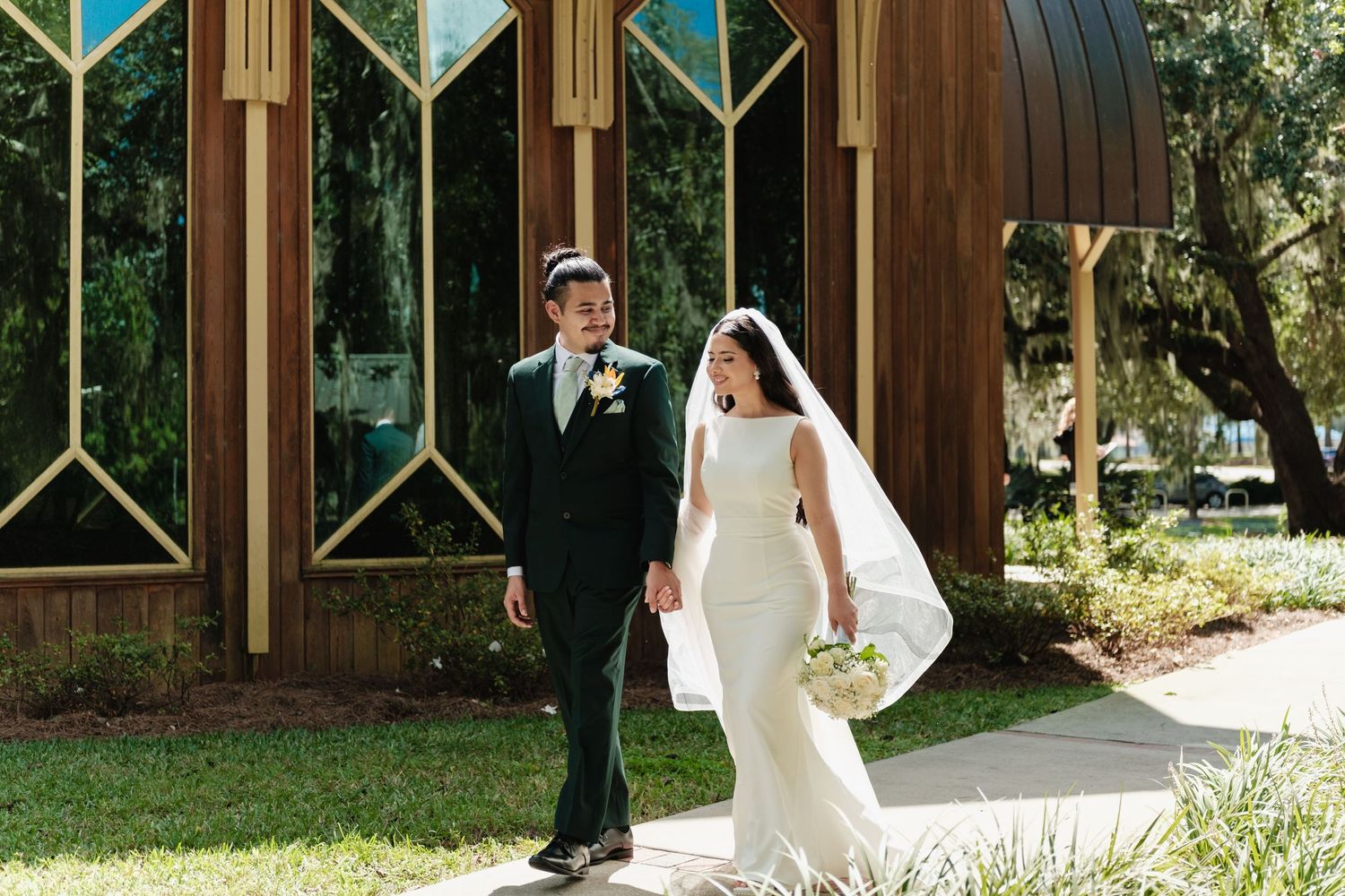 Wedding couple walking and posing along wooden architectural pathway.
