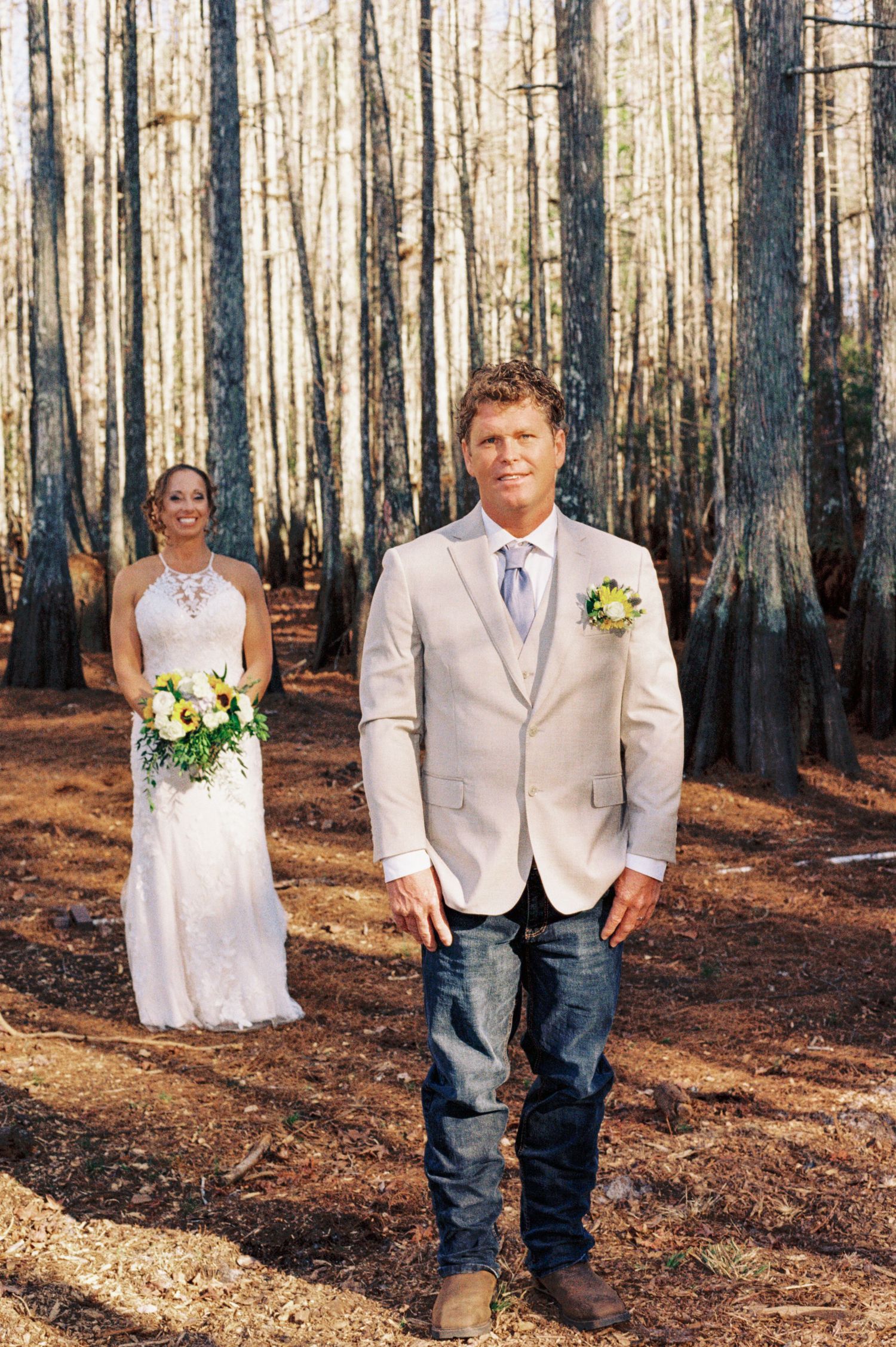 Bride and groom first look moment in a scenic cypress forest, bride holding yellow floral bouquet.