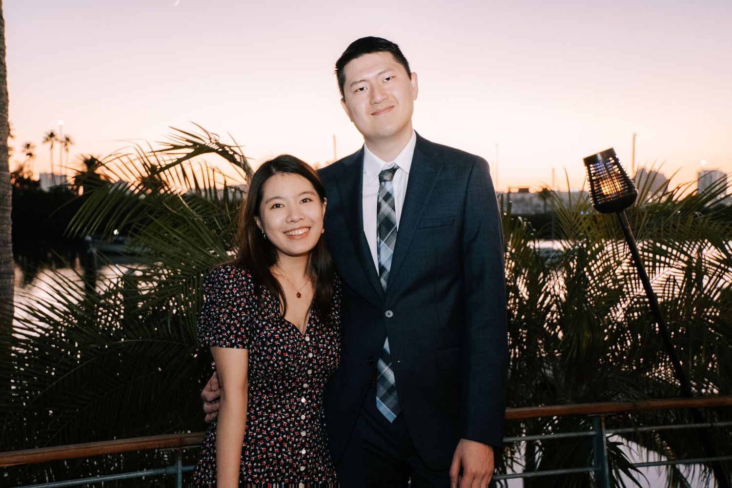 Guests in formal attire pose for photos at an elegant outdoor evening event.