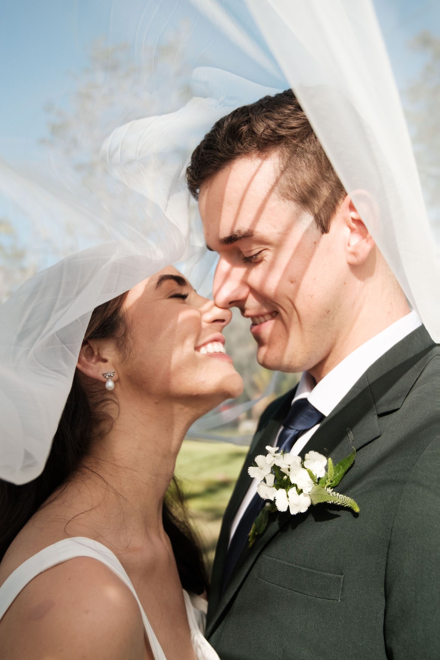 Close-up wedding photos show romantic moments between a bride and groom against a bright sky background.