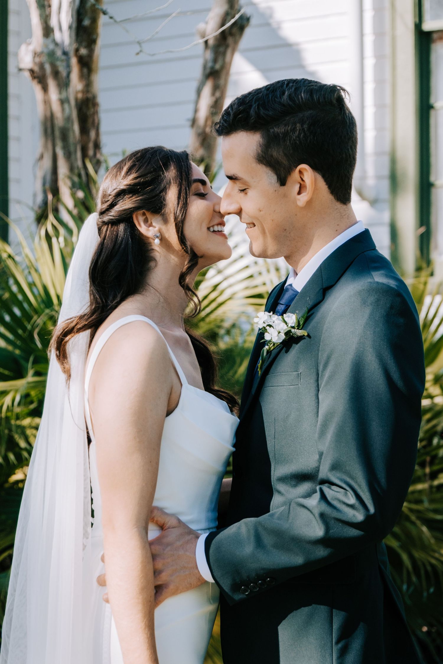 A romantic wedding photo sequence showing tender moments between newlyweds against a white building.