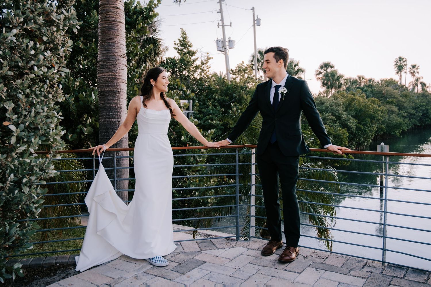 Romantic wedding couple portraits captured on an outdoor terrace with palm trees and railing.
