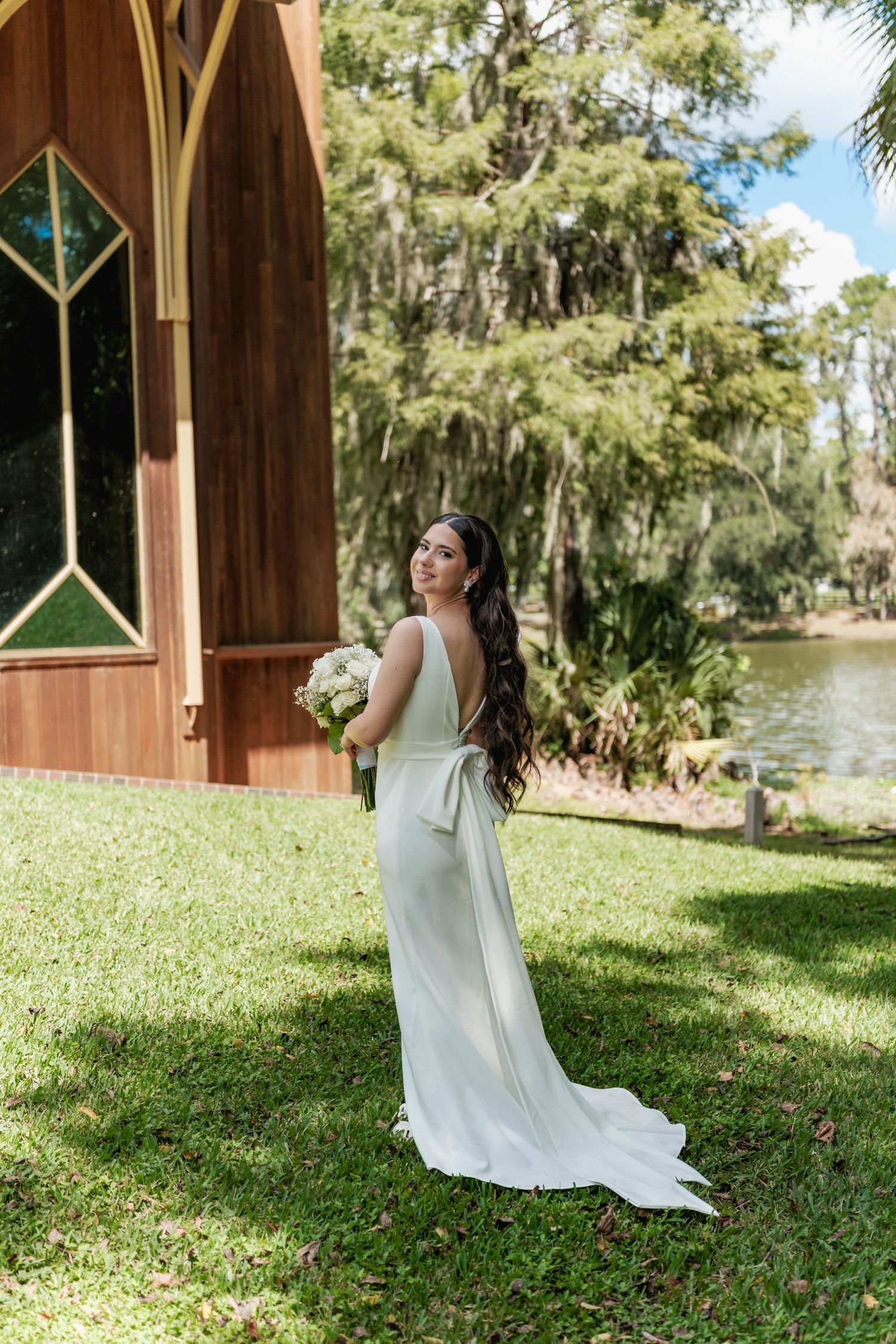 A serene bridal portrait session in a white gown near a wooden gazebo by the water.