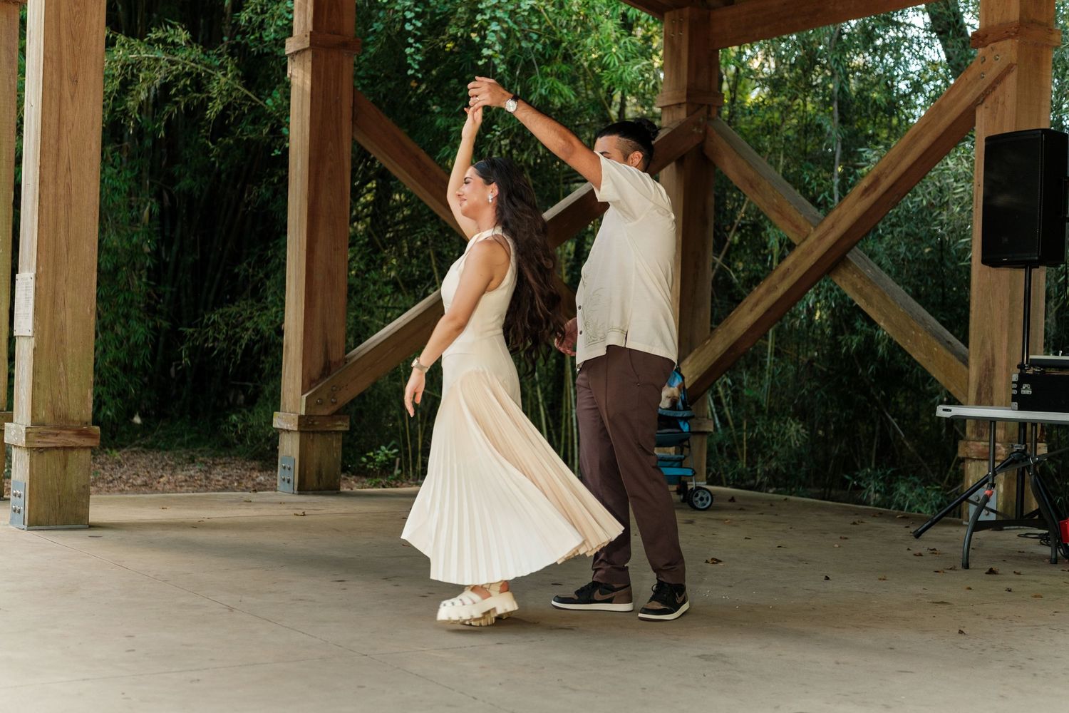 Couples dancing together under a wooden pavilion during a wedding celebration.