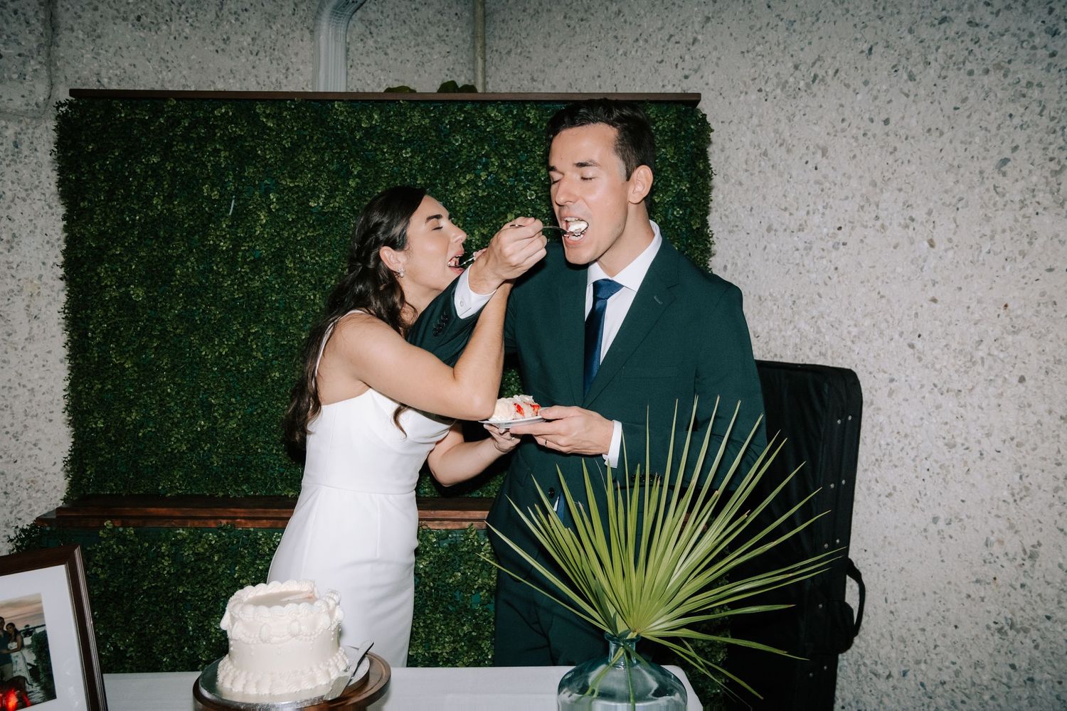 Wedding celebration on an outdoor patio with greenery wall and modern decor.