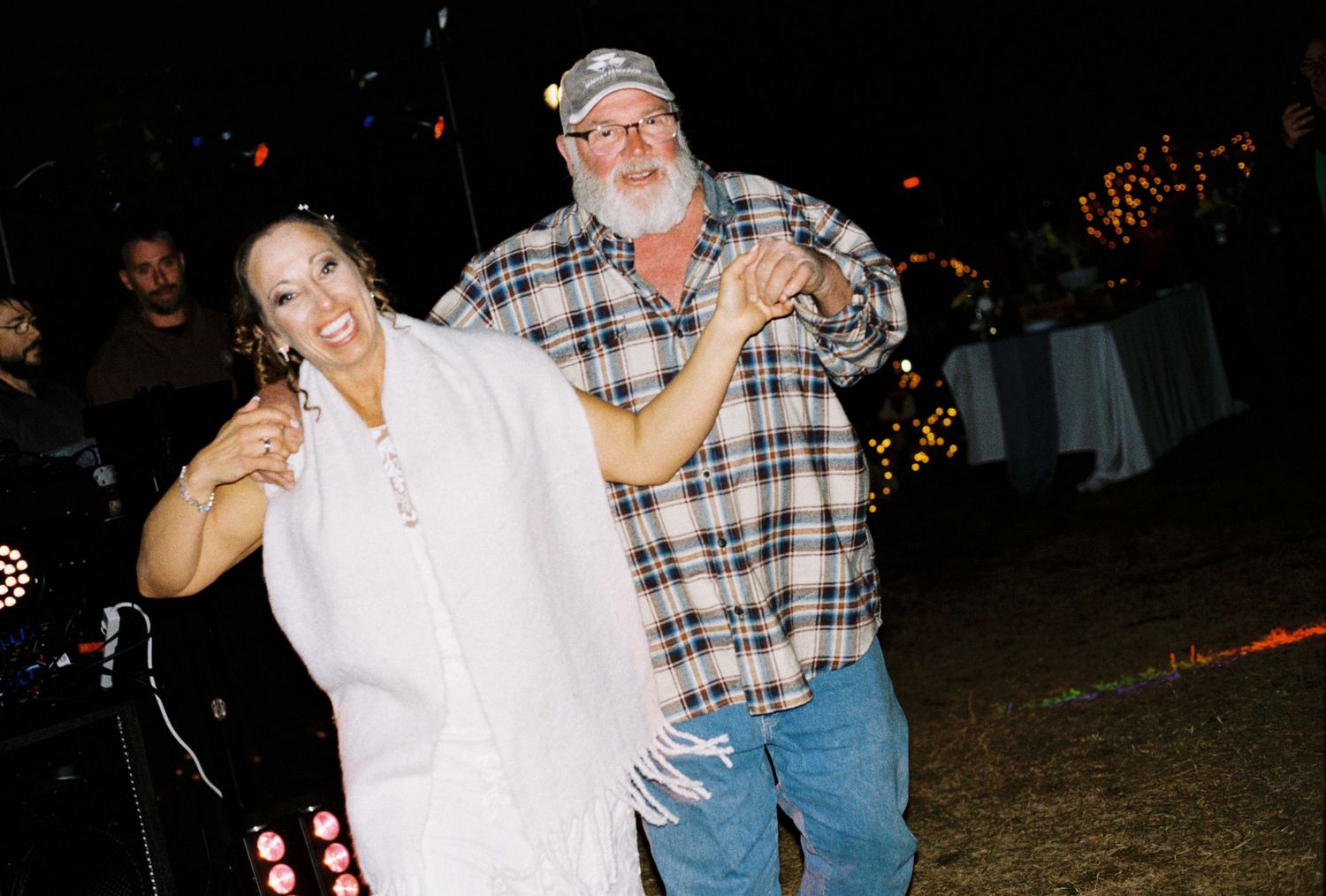 Couple dancing together outdoors at a nighttime celebration event.