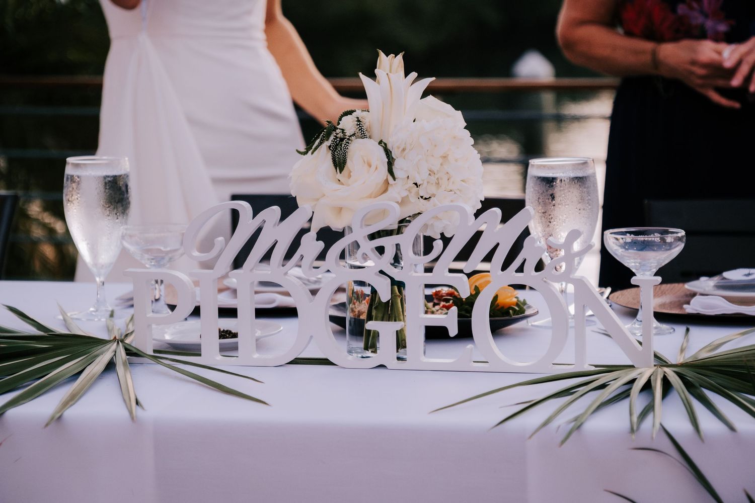 Wedding reception table settings with elegant glassware and white floral centerpieces.