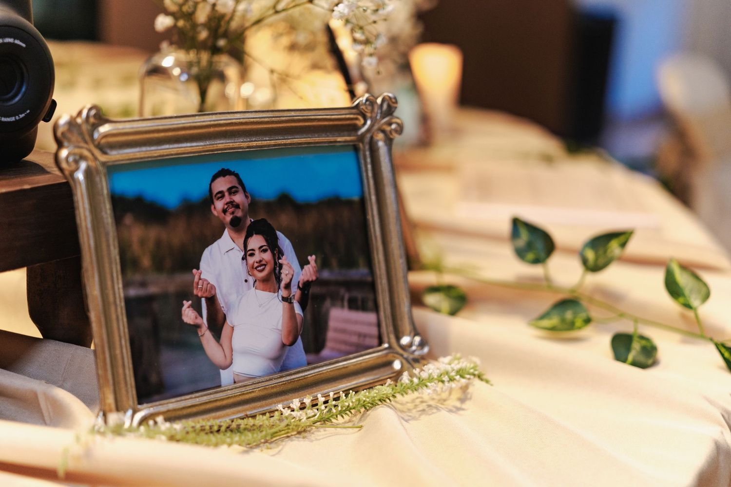 Decorative framed photos displayed on a white tablecloth with green leaf accents.