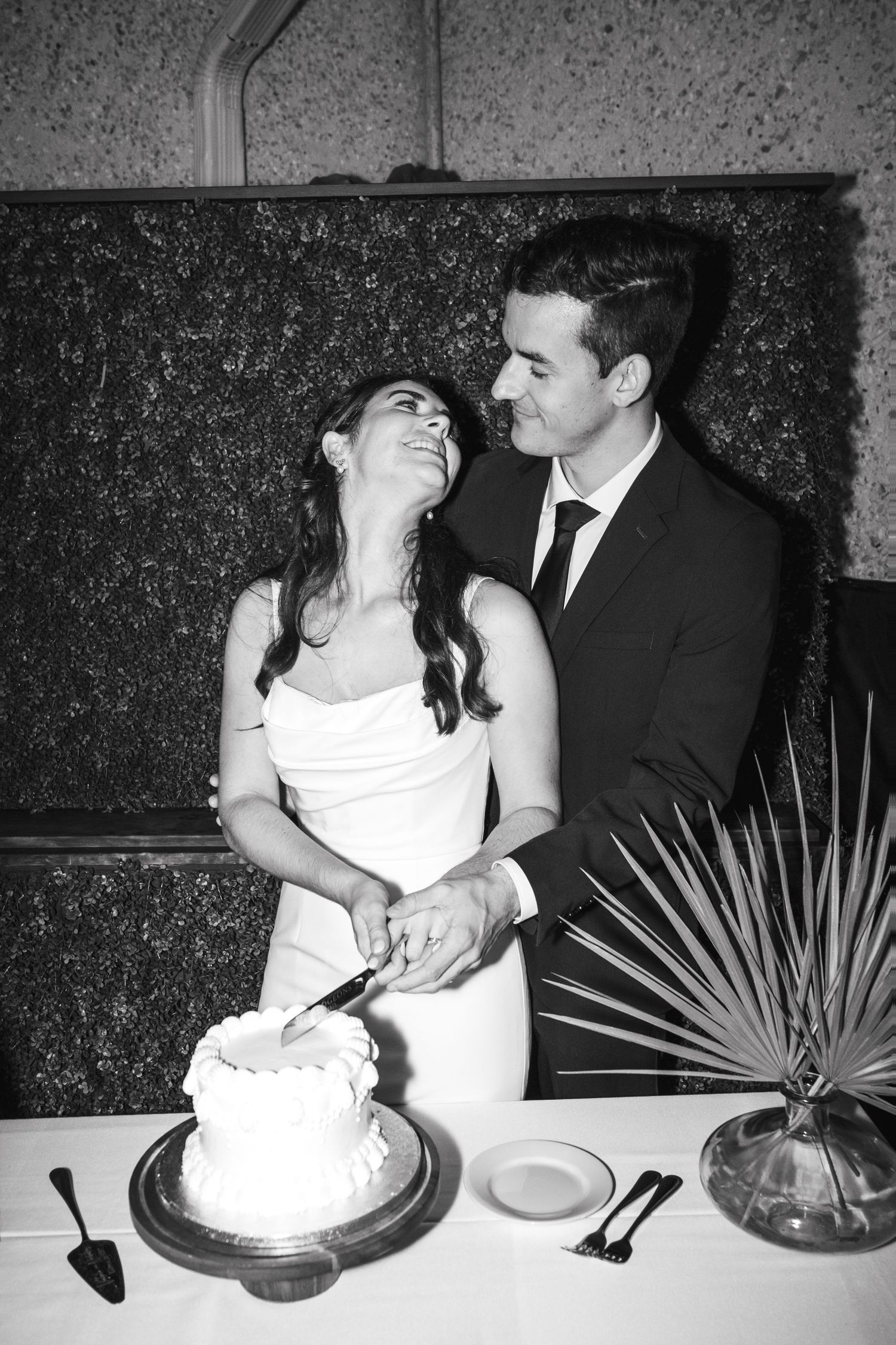 Black and white photos of newlyweds cutting their wedding cake together at the reception.
