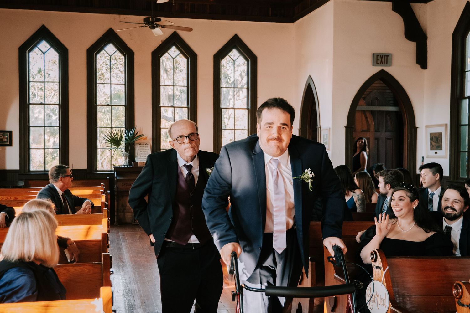 People gather in an elegant church hall with arched windows and wooden beams for a formal event.