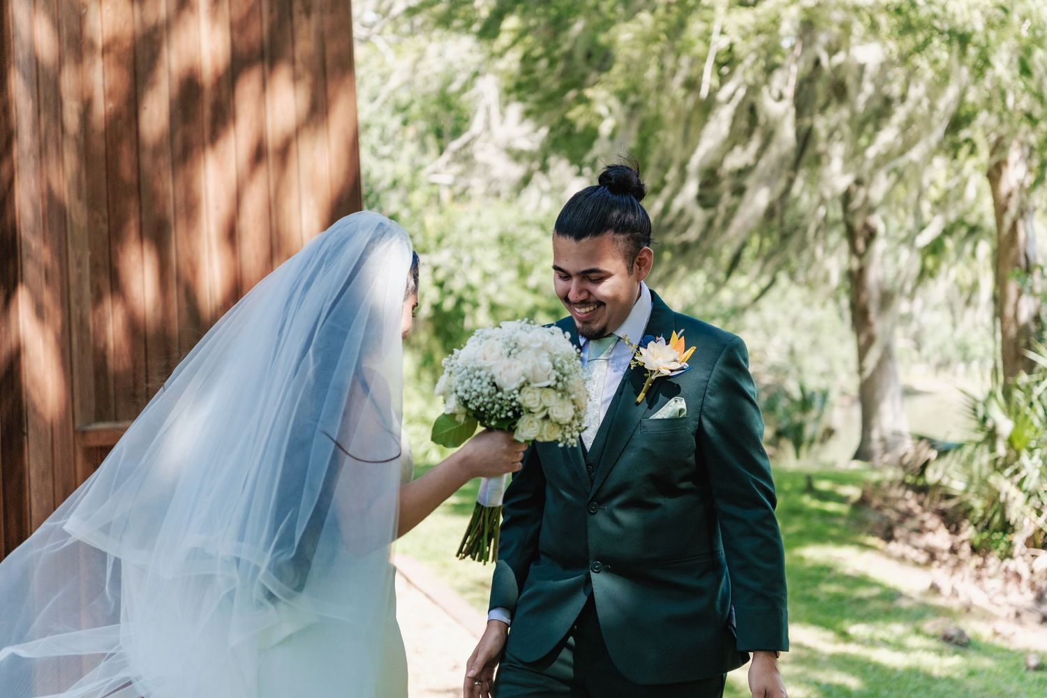 A couple shares an intimate moment under a flowing veil in an outdoor garden setting.