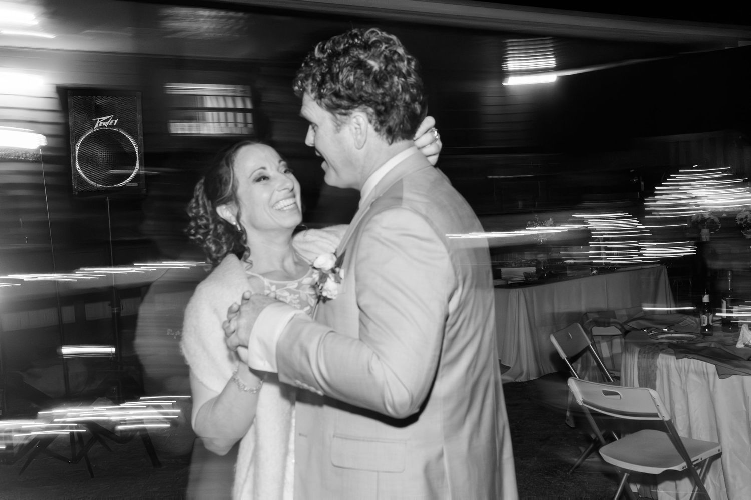 Bride and groom share romantic first dance in black and white photo at wedding reception.