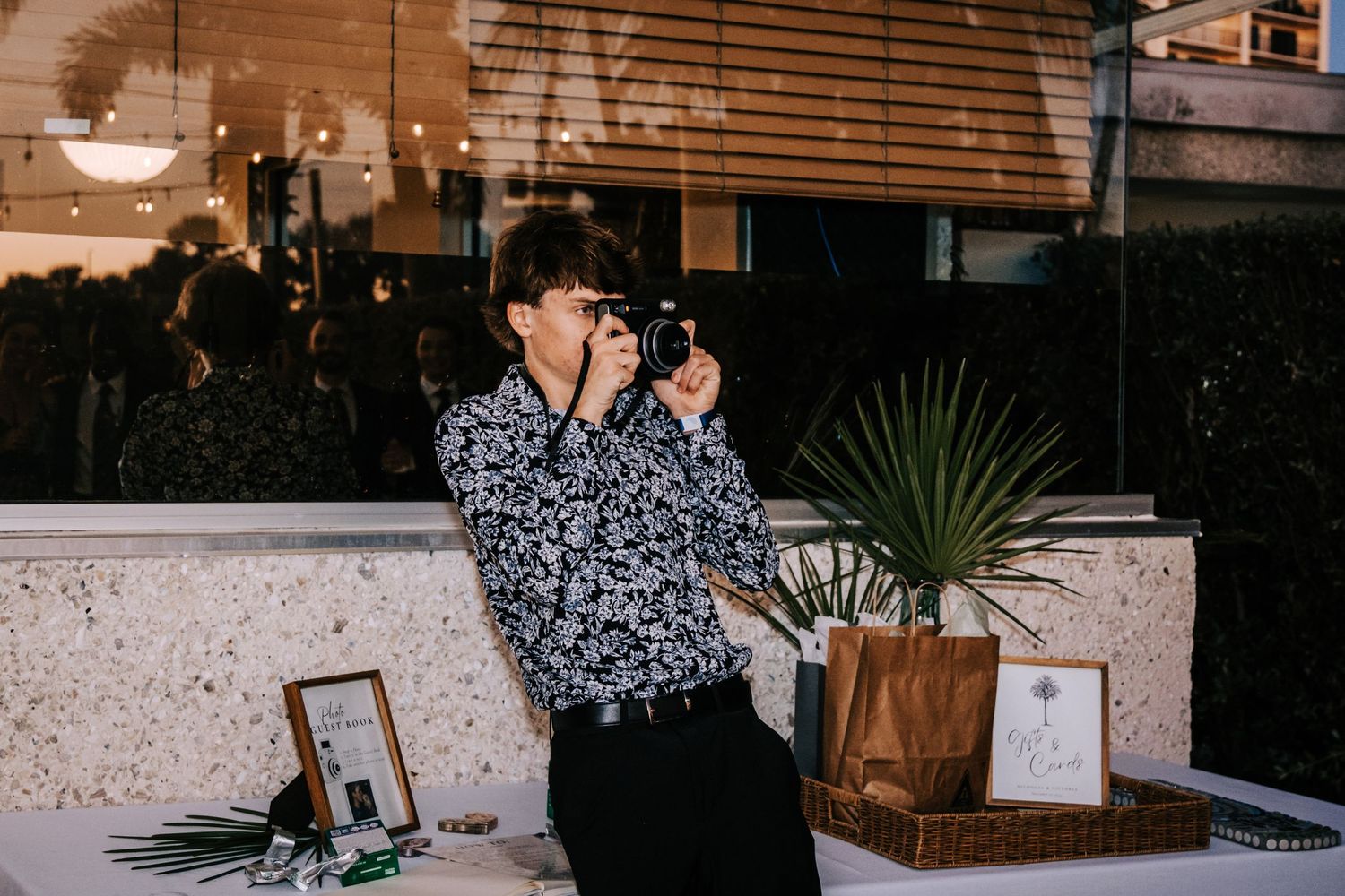 A photographer in a patterned shirt captures moments at an evening event.