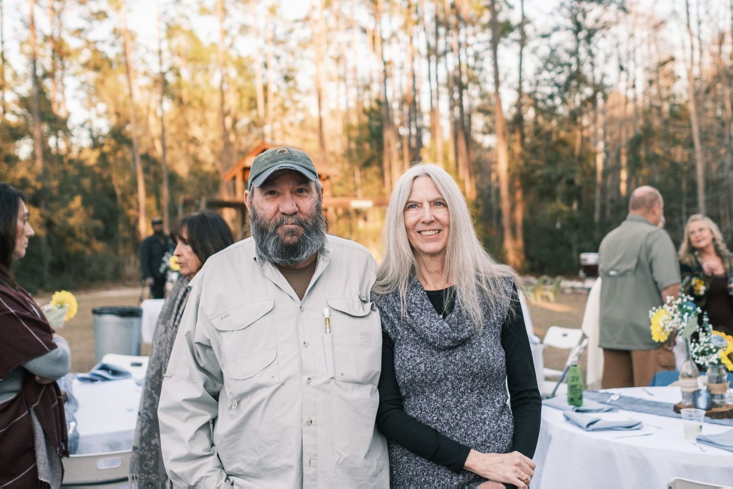 Couple posing together outdoors at a rustic woodland reception event.
