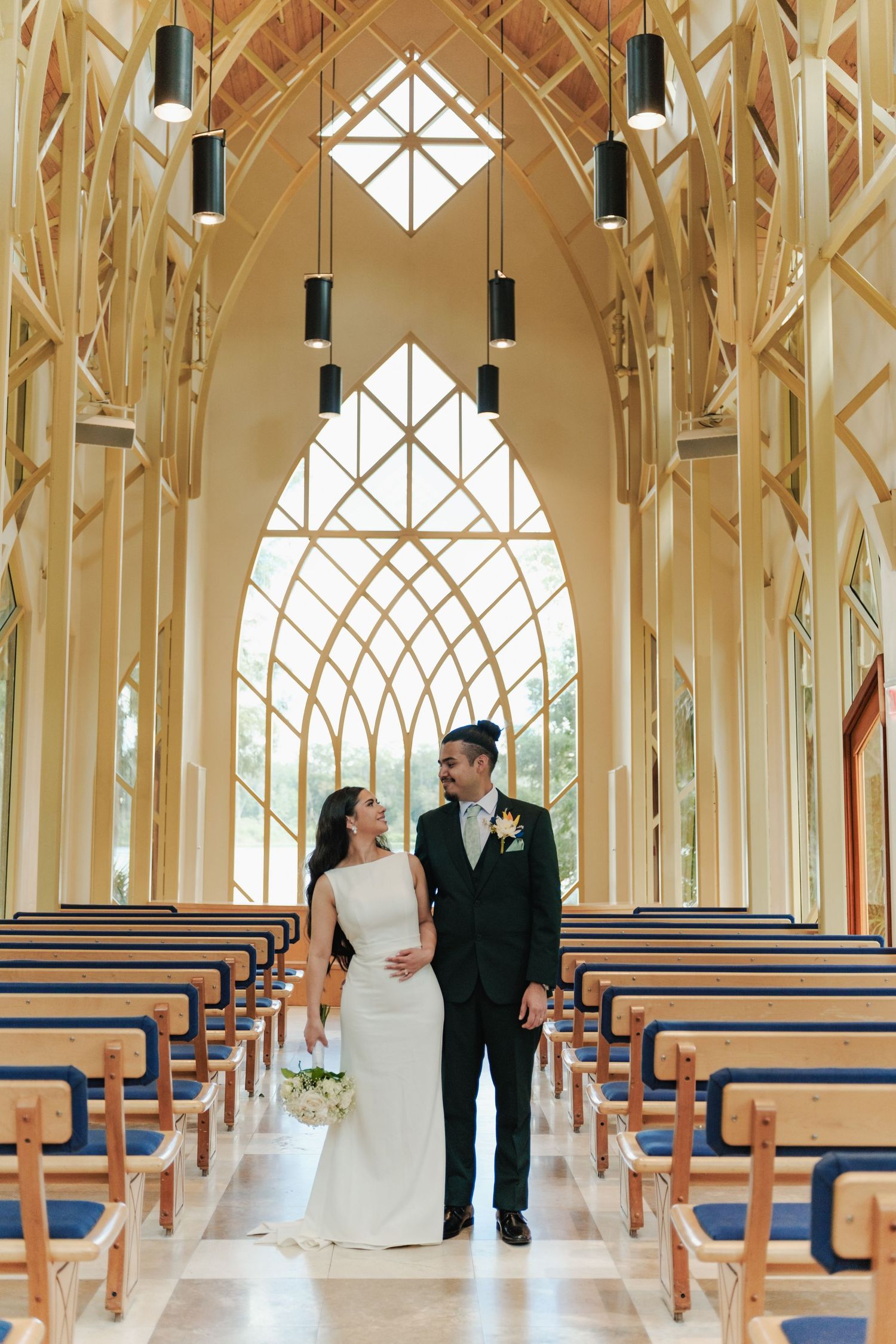 Couple shares tender moment in modern chapel with dramatic architectural features.