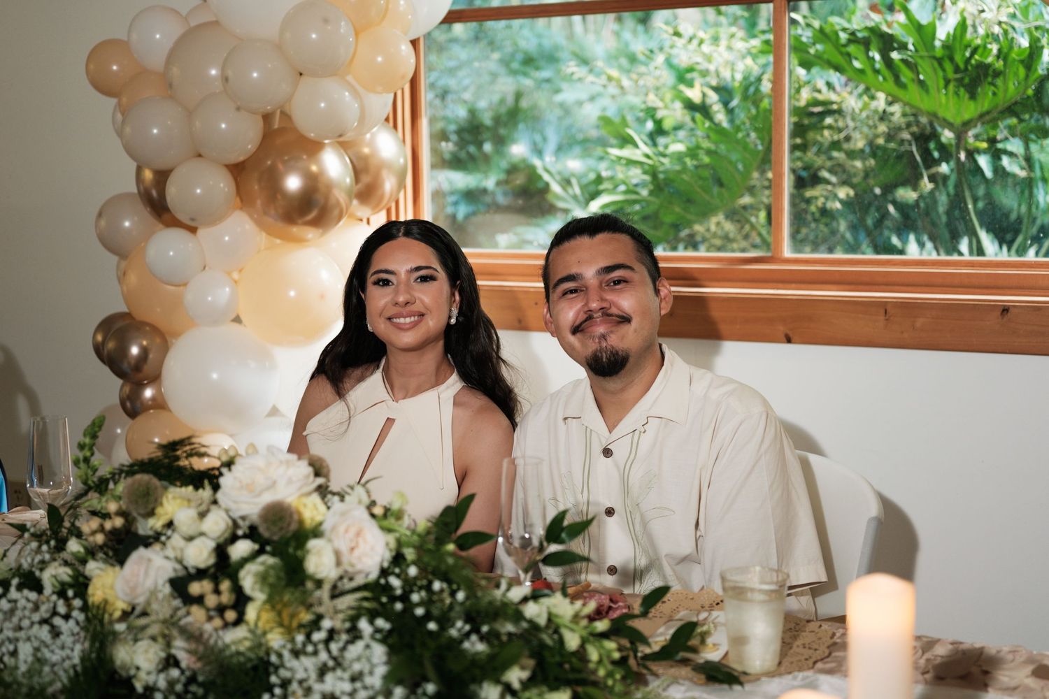 Elegant wedding reception setup with white balloon arch and floral decorations.