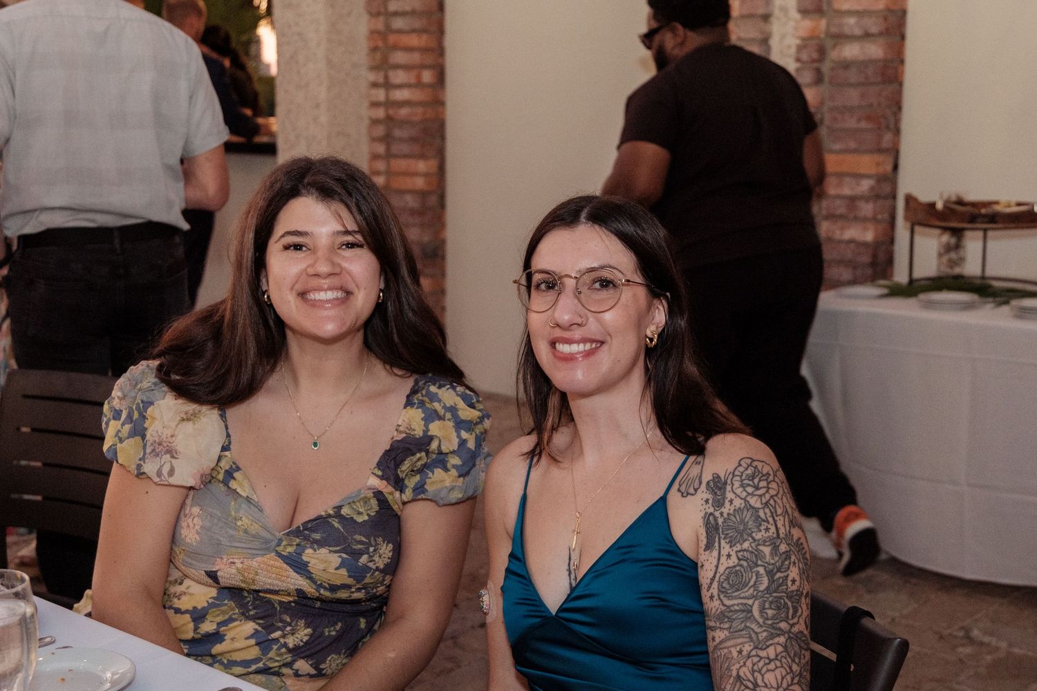 Guests enjoying themselves at an indoor wedding reception with brick walls and festive lighting.