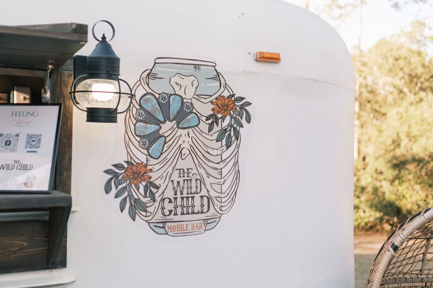 The Wild Child mobile bar vintage trailer with floral ribcage artwork at outdoor wedding.
