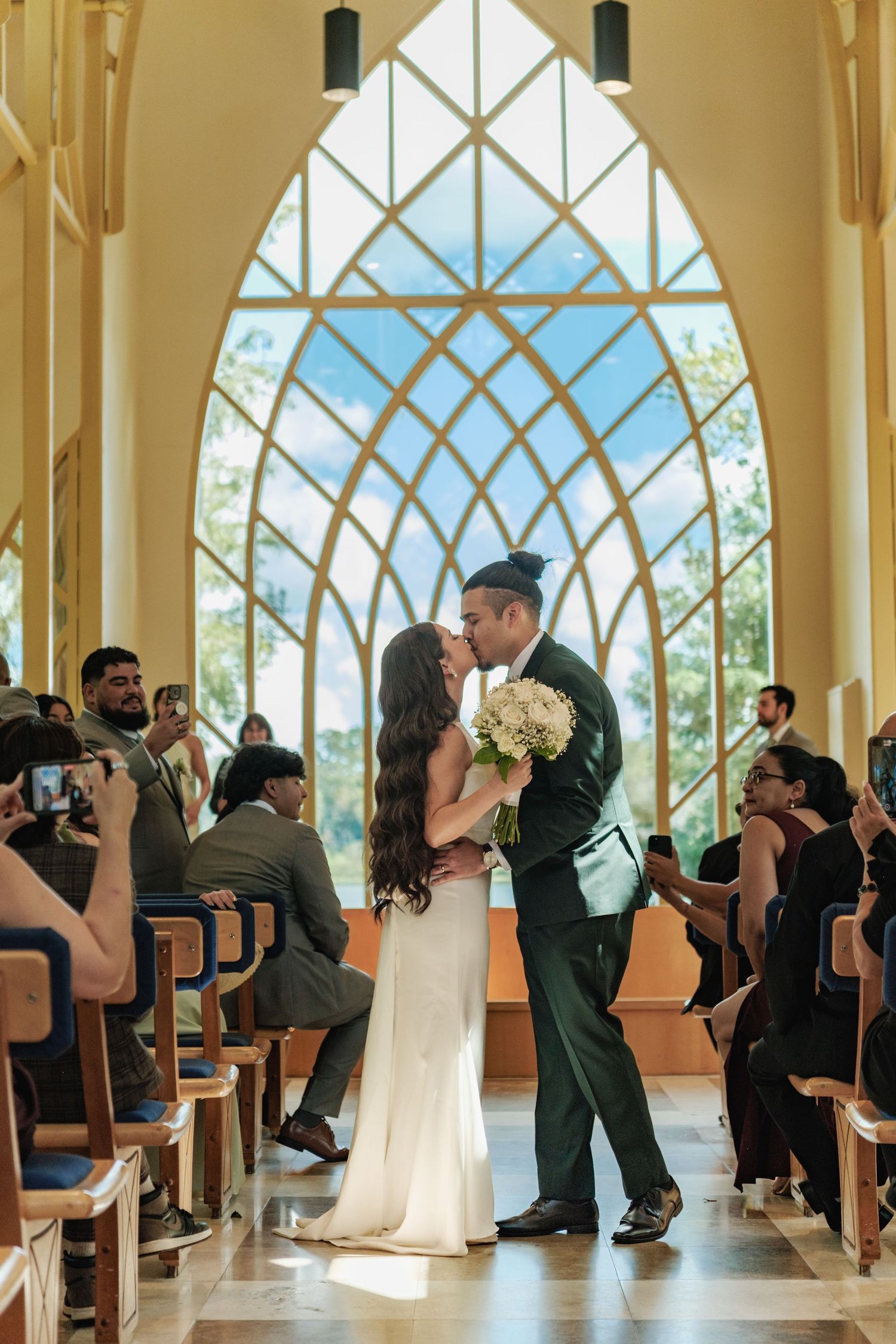 Wedding ceremony in a modern chapel with dramatic arched windows and wooden beams.