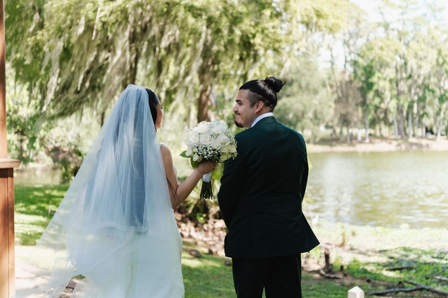 Wedding couple sharing a private moment by a lake with Spanish moss trees in background.