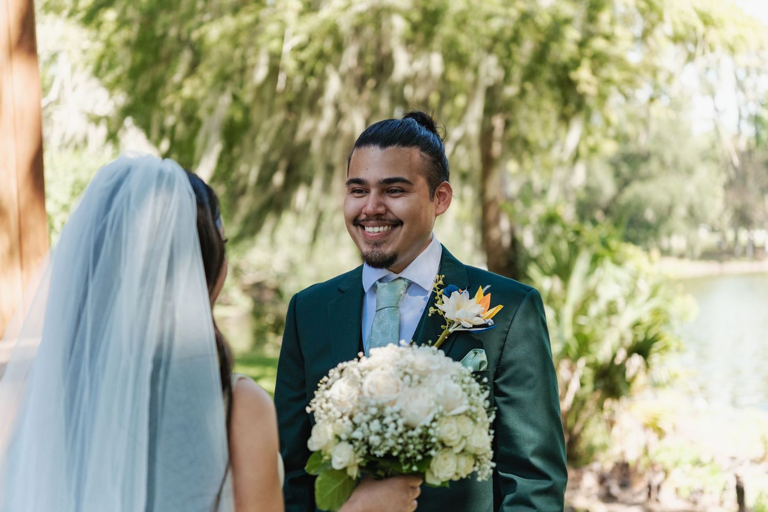 Wedding couple sharing joyful moment outdoors with white floral bouquet.