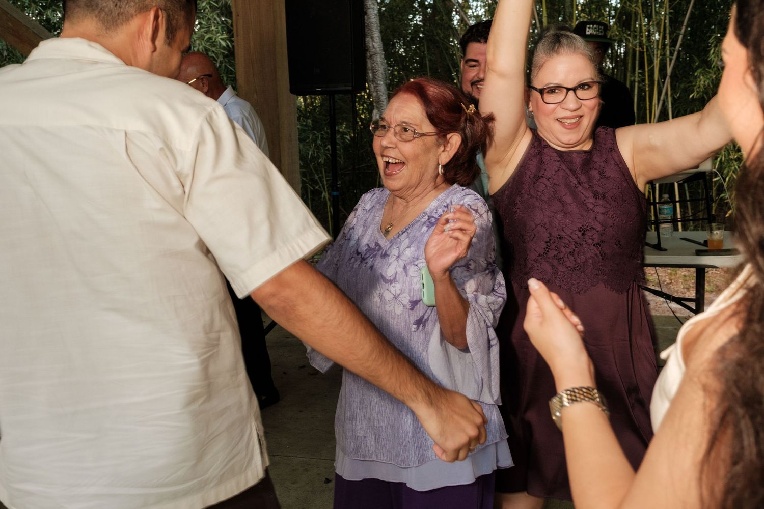 Guests dancing and celebrating at a lively wedding reception under covered outdoor space.