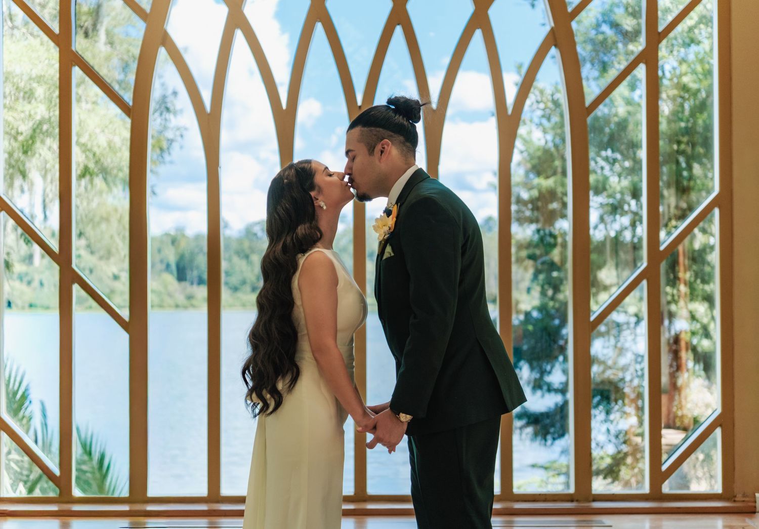 Wedding couple standing by wooden arches overlooking waterfront view.