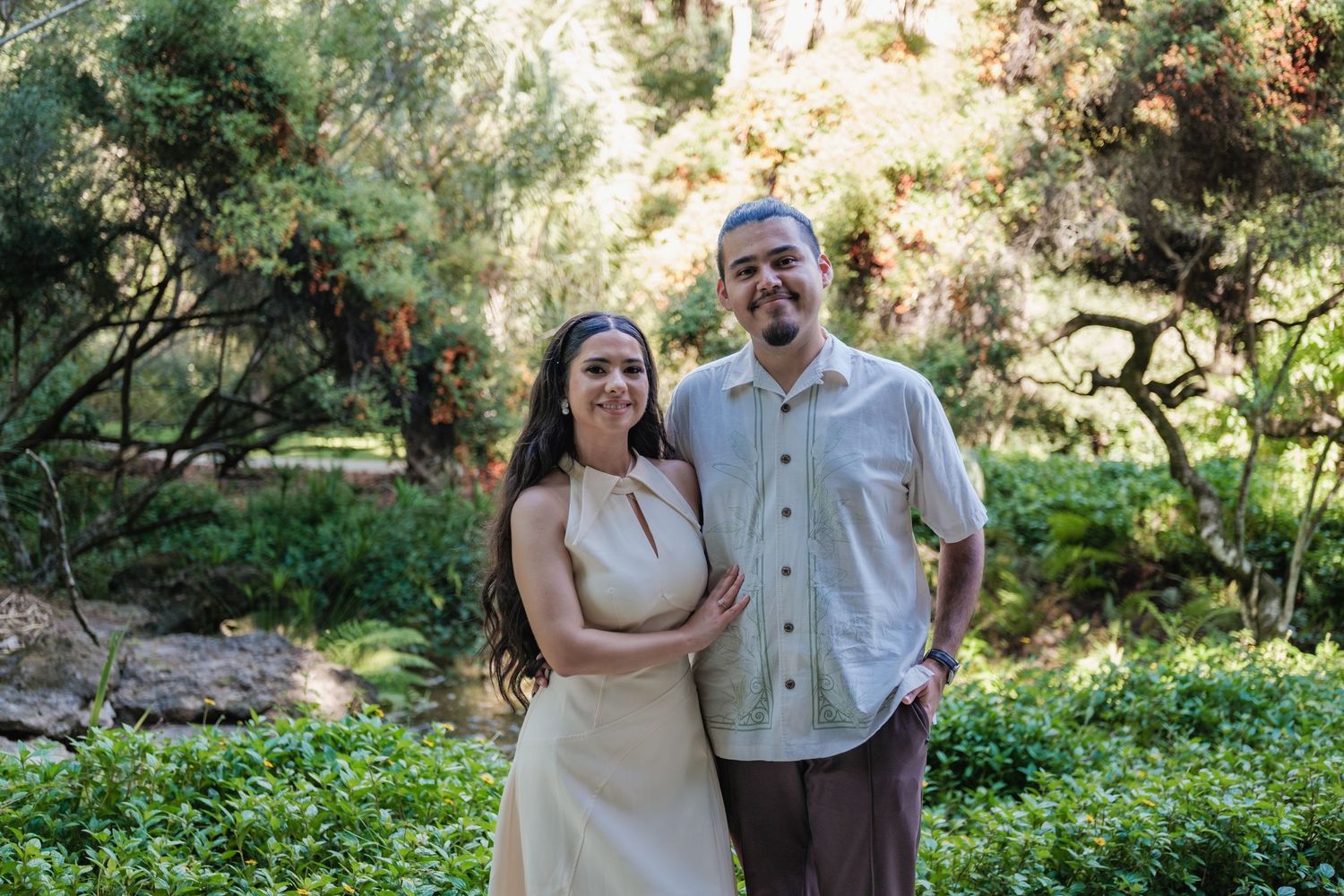 A couple poses for romantic outdoor wedding photos in a lush garden setting.