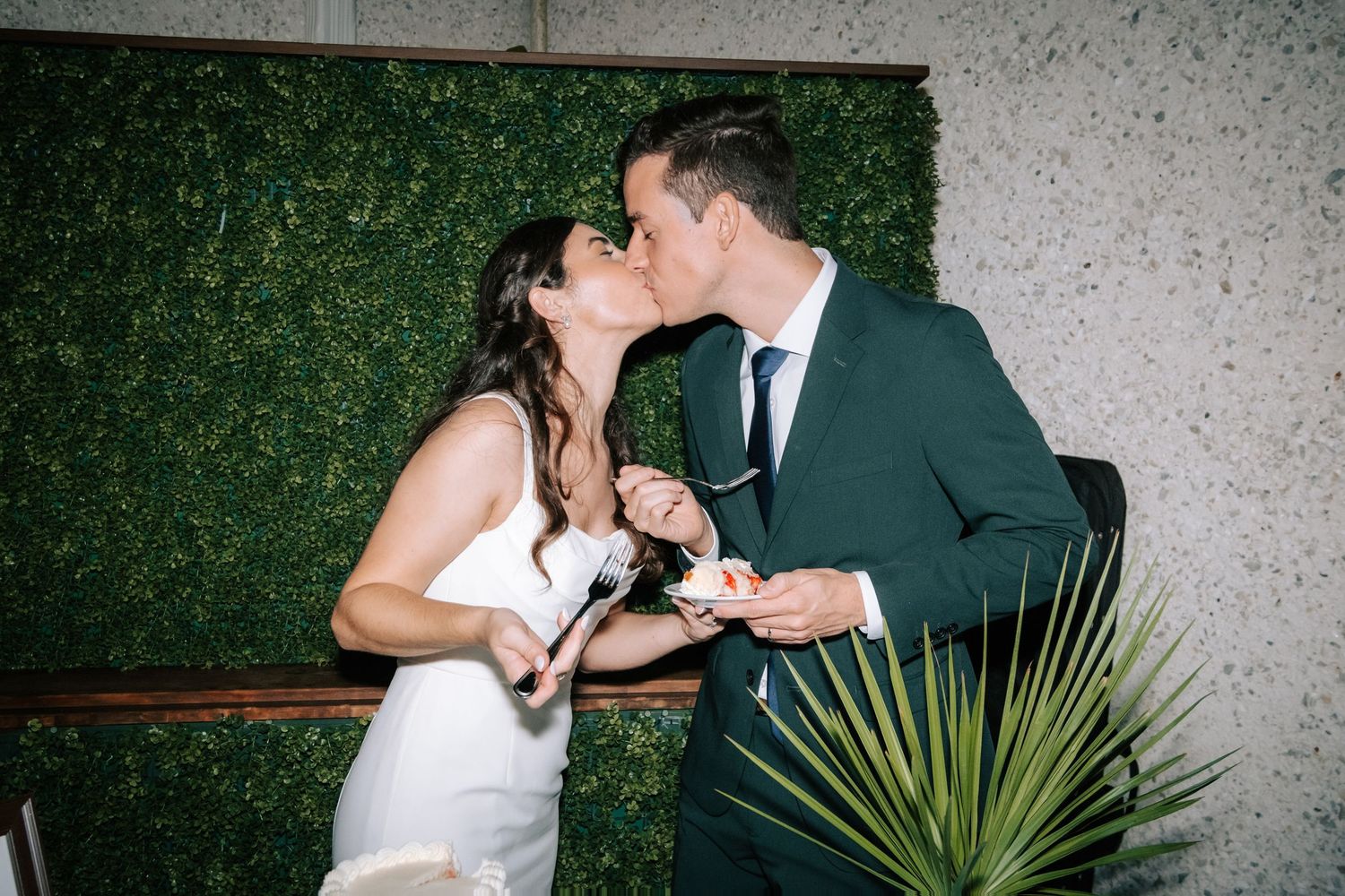 A couple shares a romantic moment while cutting their wedding cake at their reception.