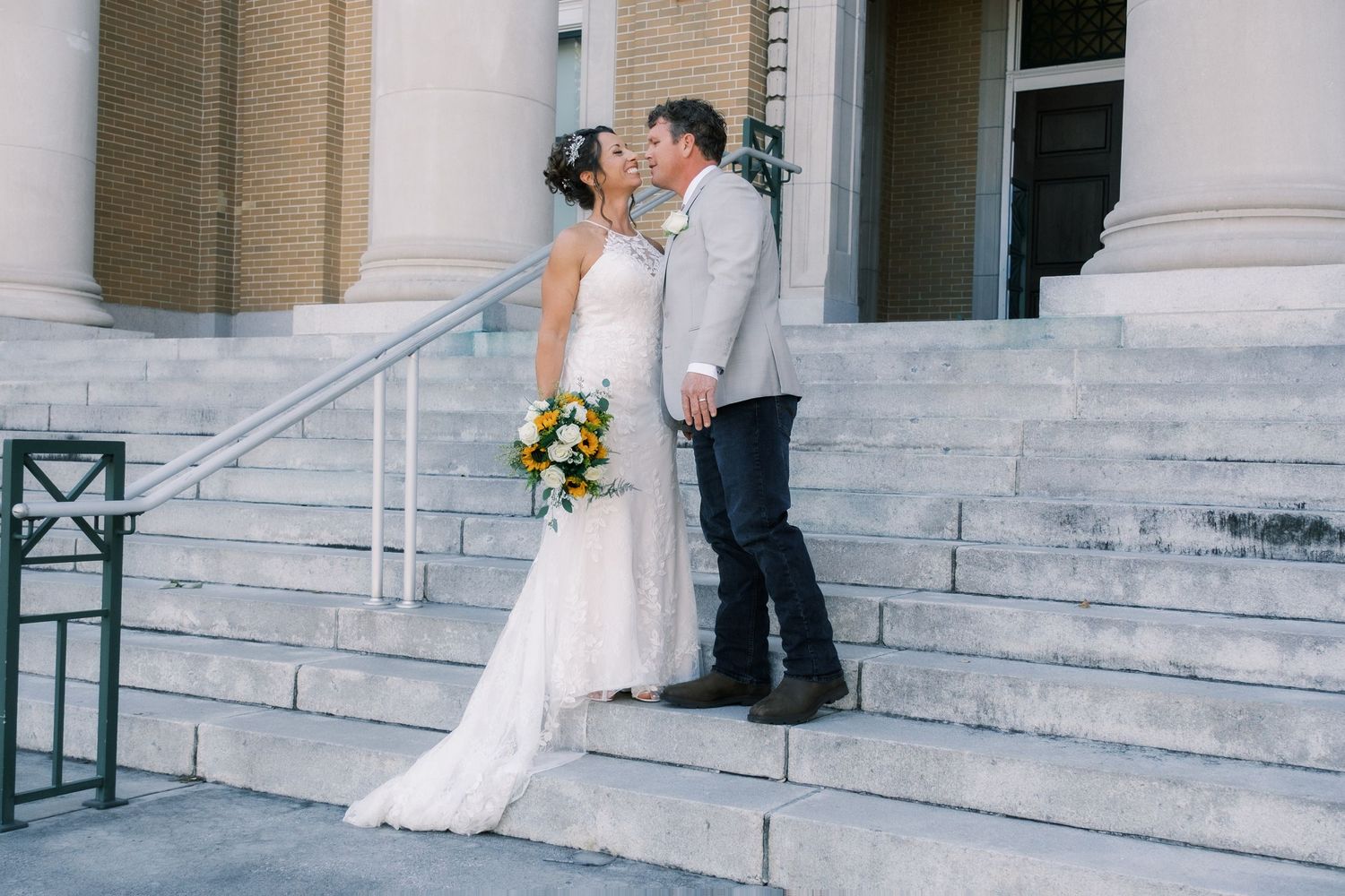 Bride and groom share a romantic kiss on the steps of a grand building on their wedding day.