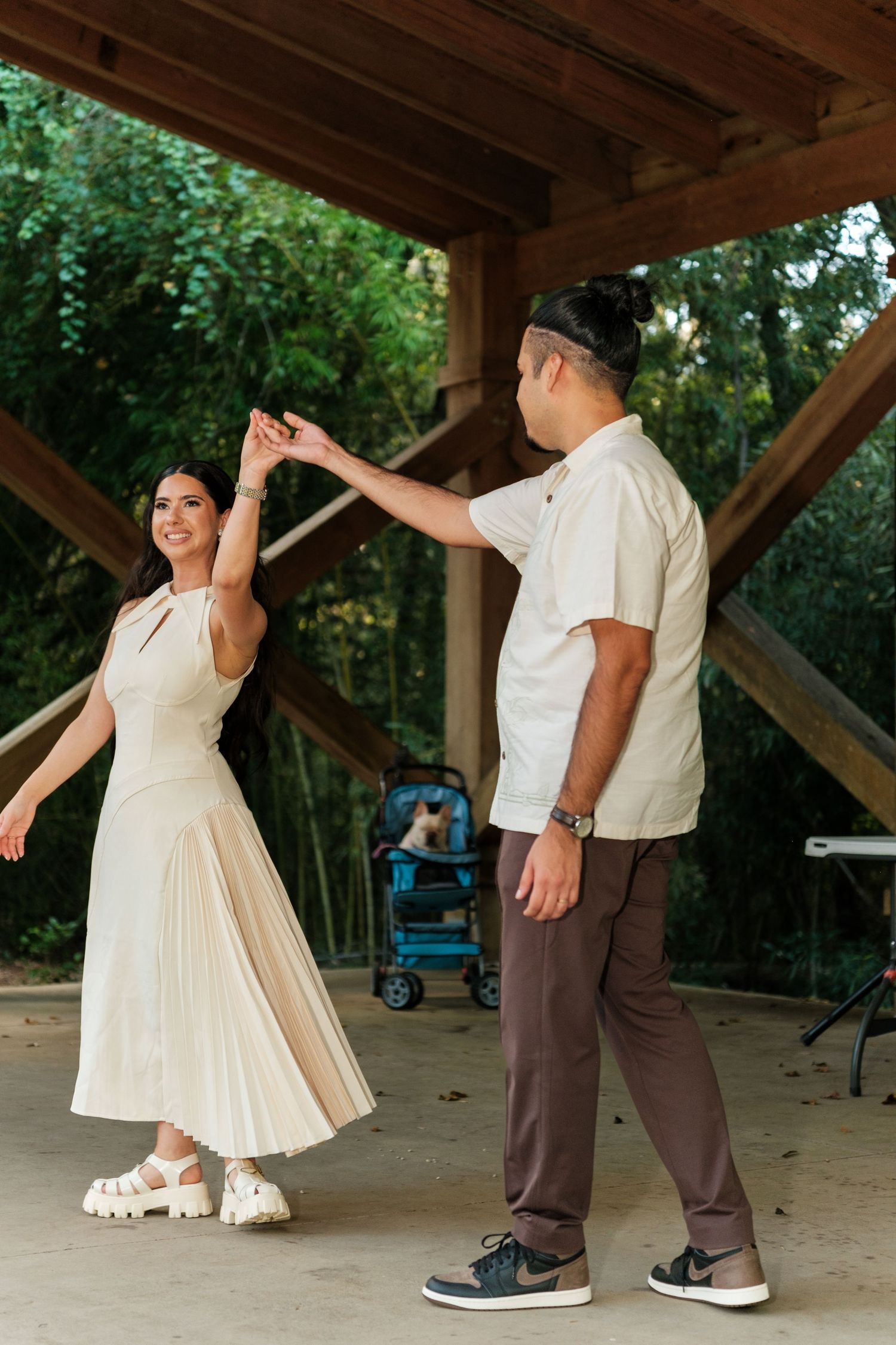 Couple dancing under a wooden pavilion in a natural outdoor setting.