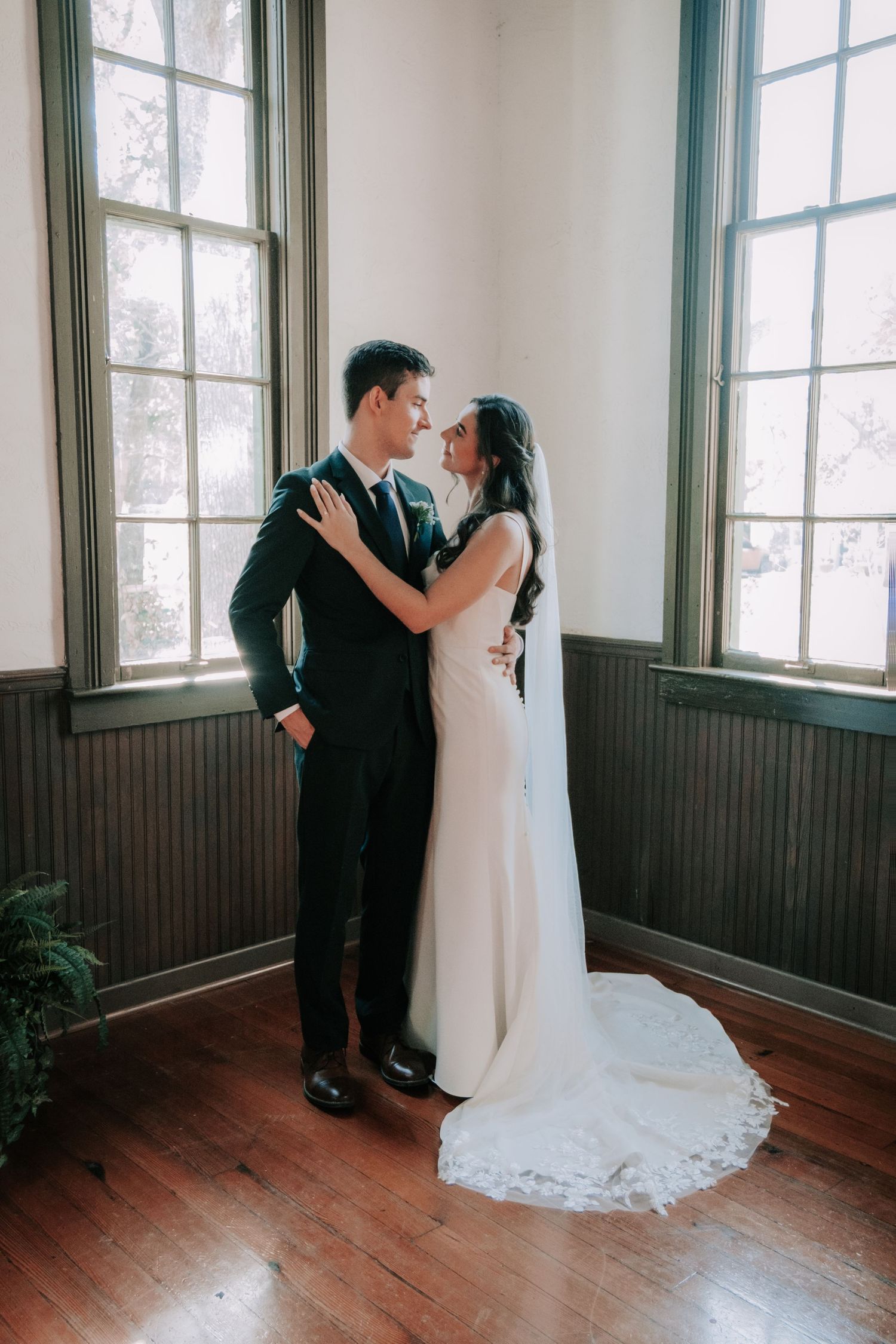 A romantic wedding photoshoot sequence showing a couple embracing in a sunlit room with wooden floors and tall windows.