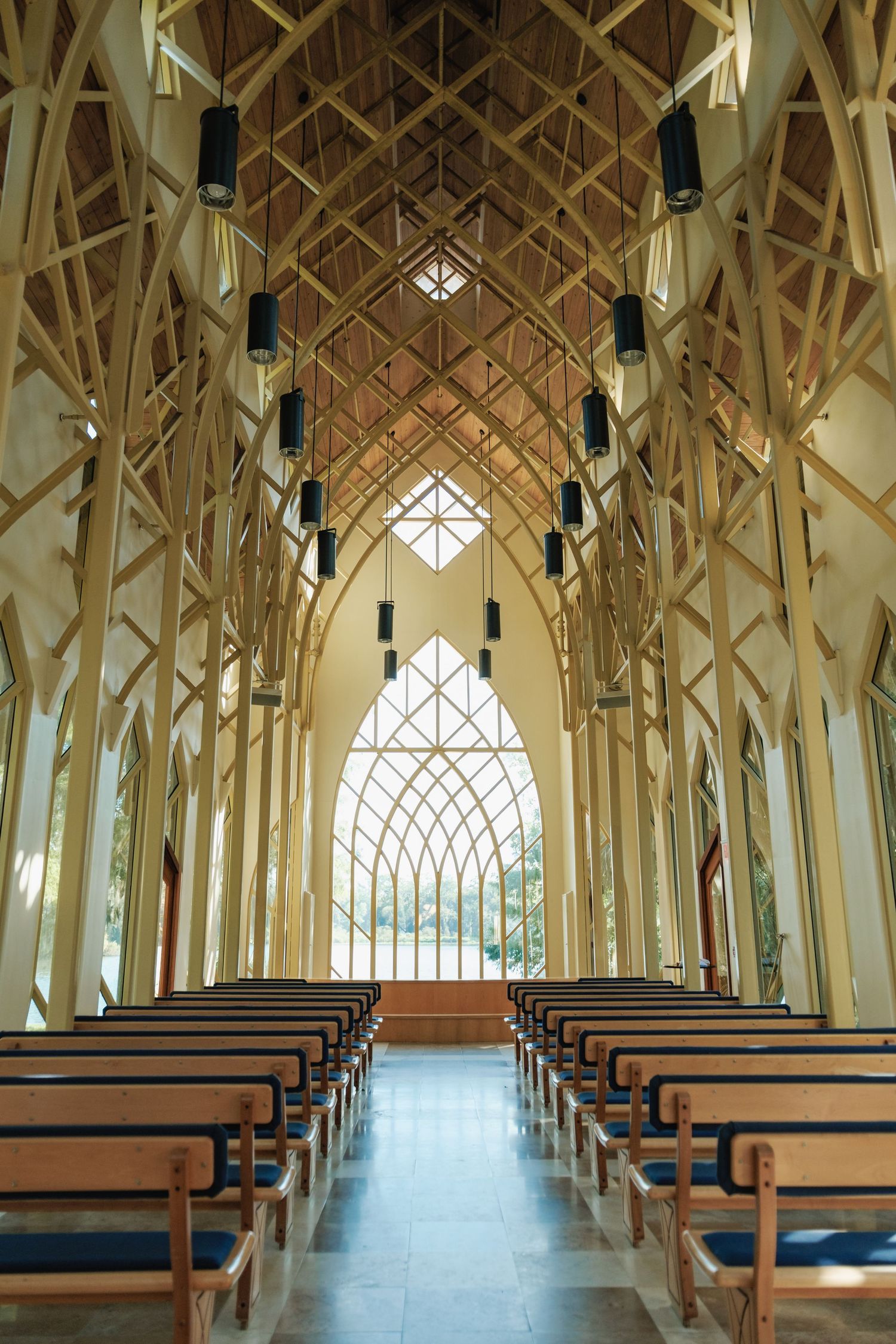 Interior of modern chapel with dramatic wooden beams and geometric windows creating stunning architectural lines.