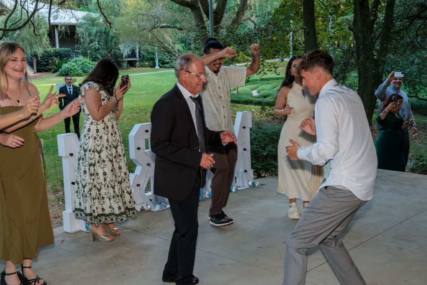 Wedding guests dancing and mingling at an outdoor covered reception venue.