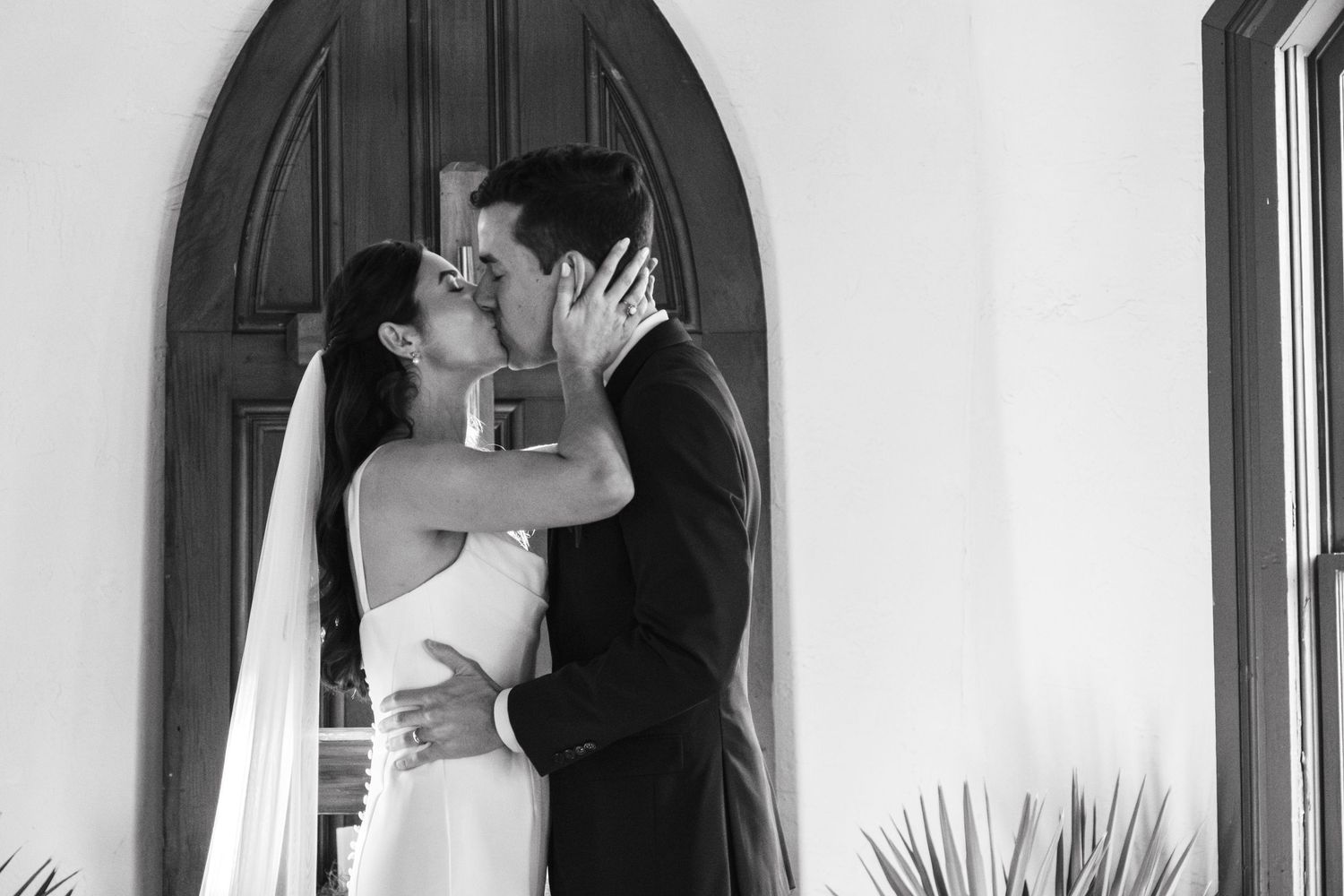 Romantic black and white wedding portrait by arched doorway.