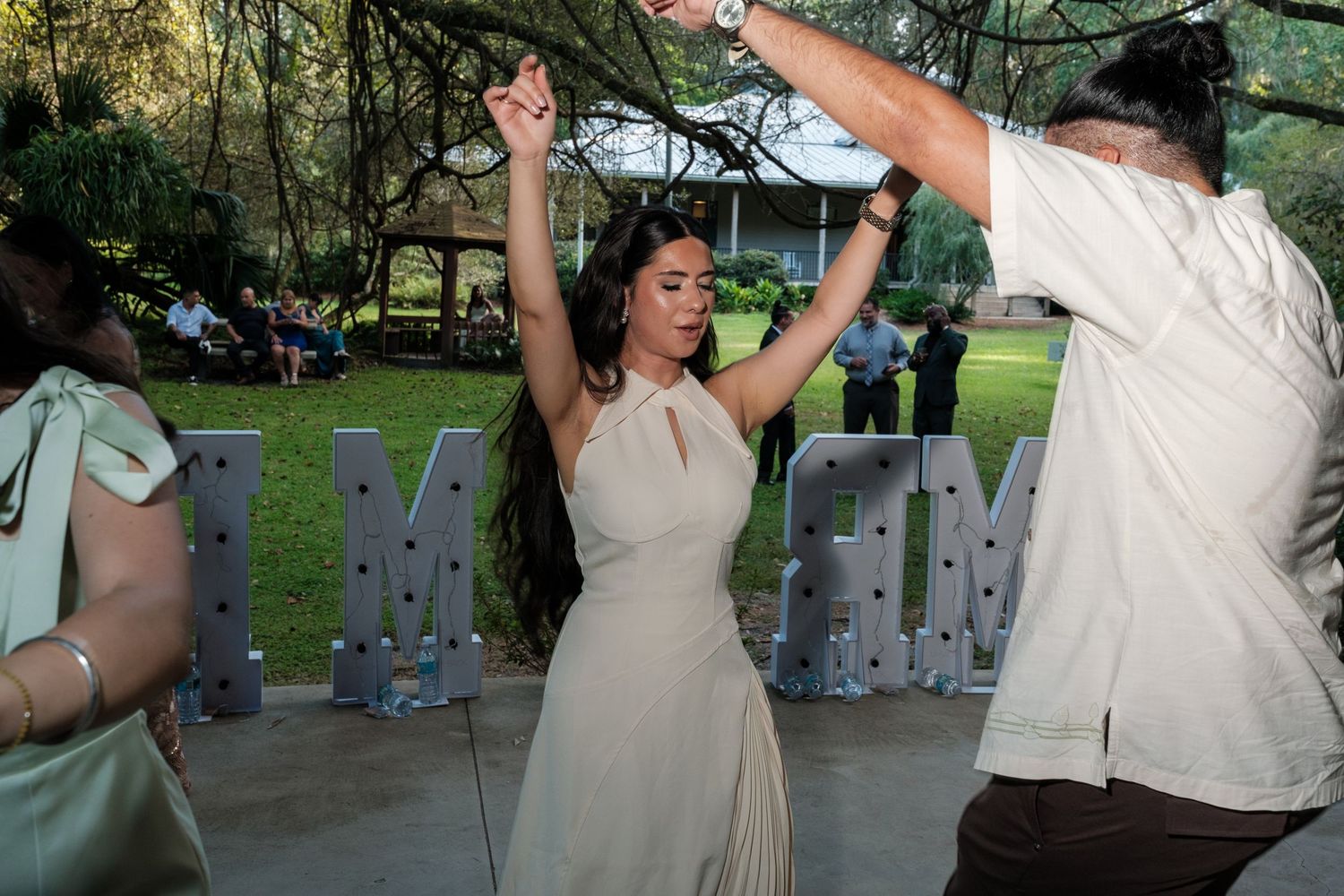 Couple dancing together at an outdoor wedding reception with joyful expressions.