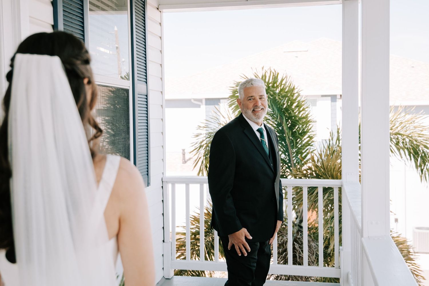 Emotional first look moment between father and bride on white porch.