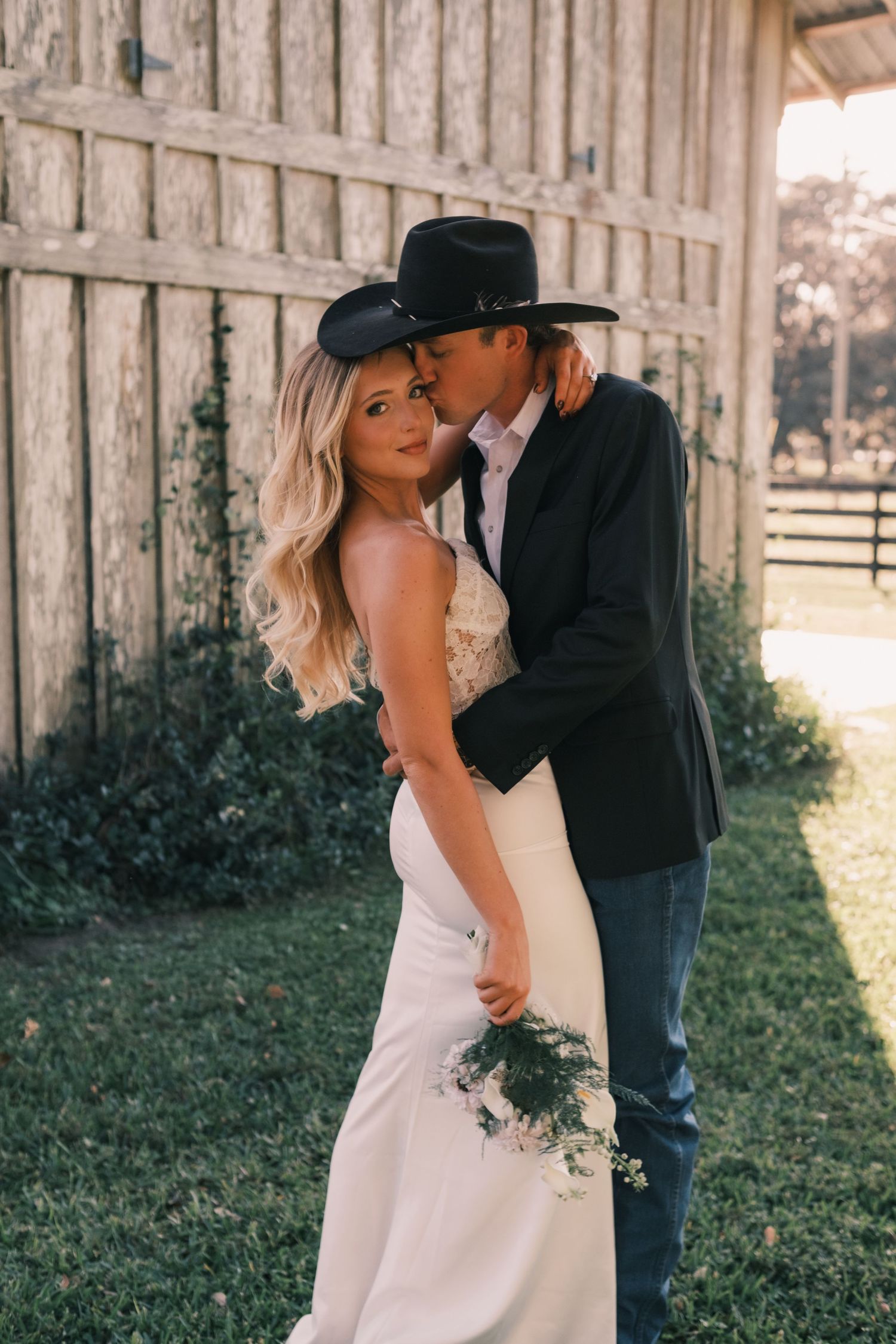 Romantic wedding moment captured against rustic wooden barn backdrop.