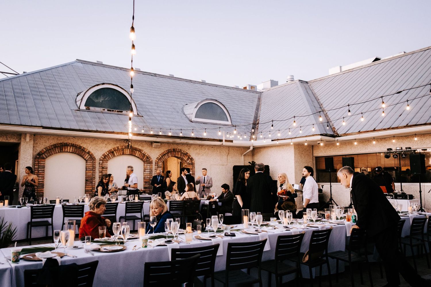 Wedding reception venue setup with string lights and white tent covering dining tables.