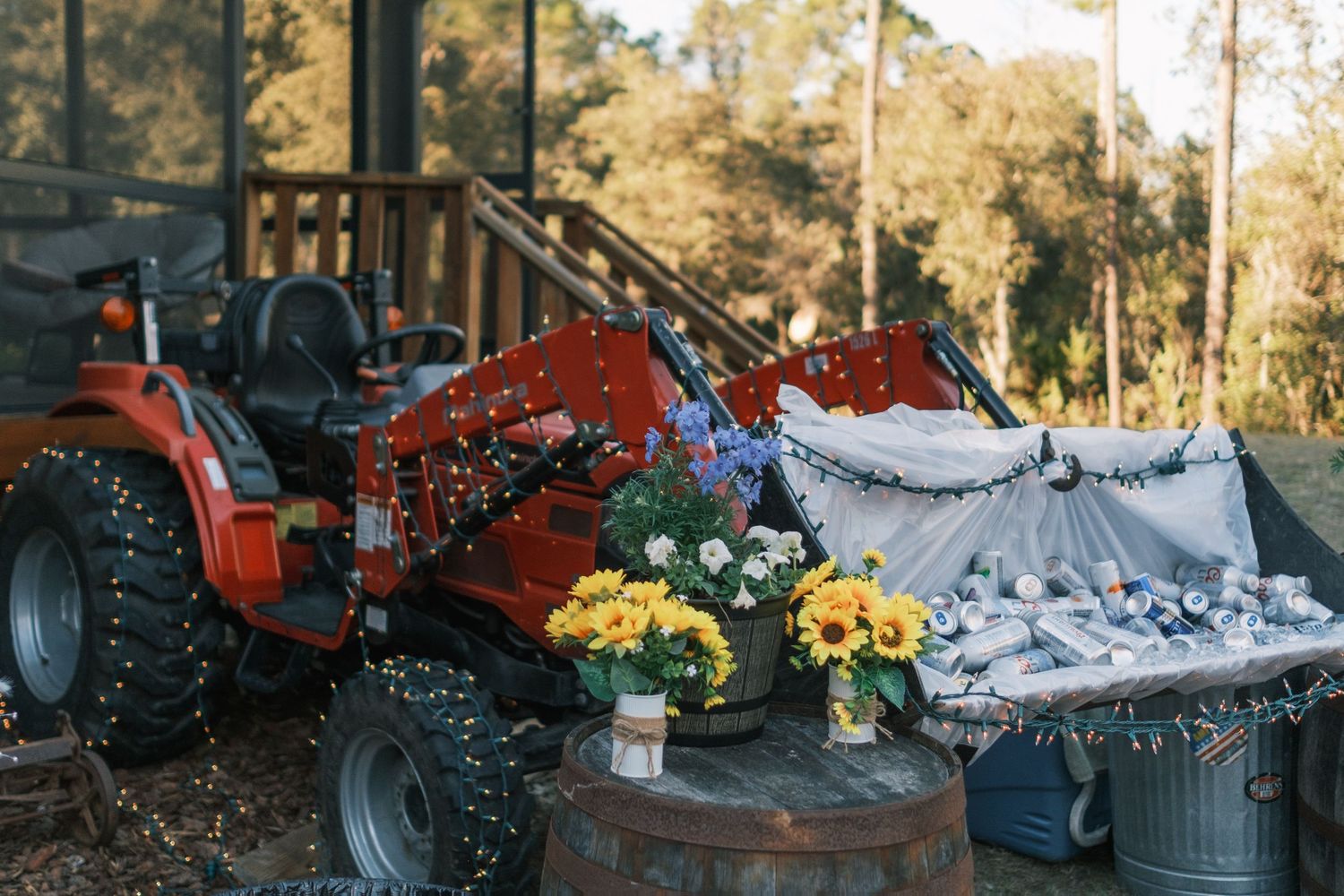 Red tractor decorated with string lights and flowers at rustic outdoor wedding reception.
