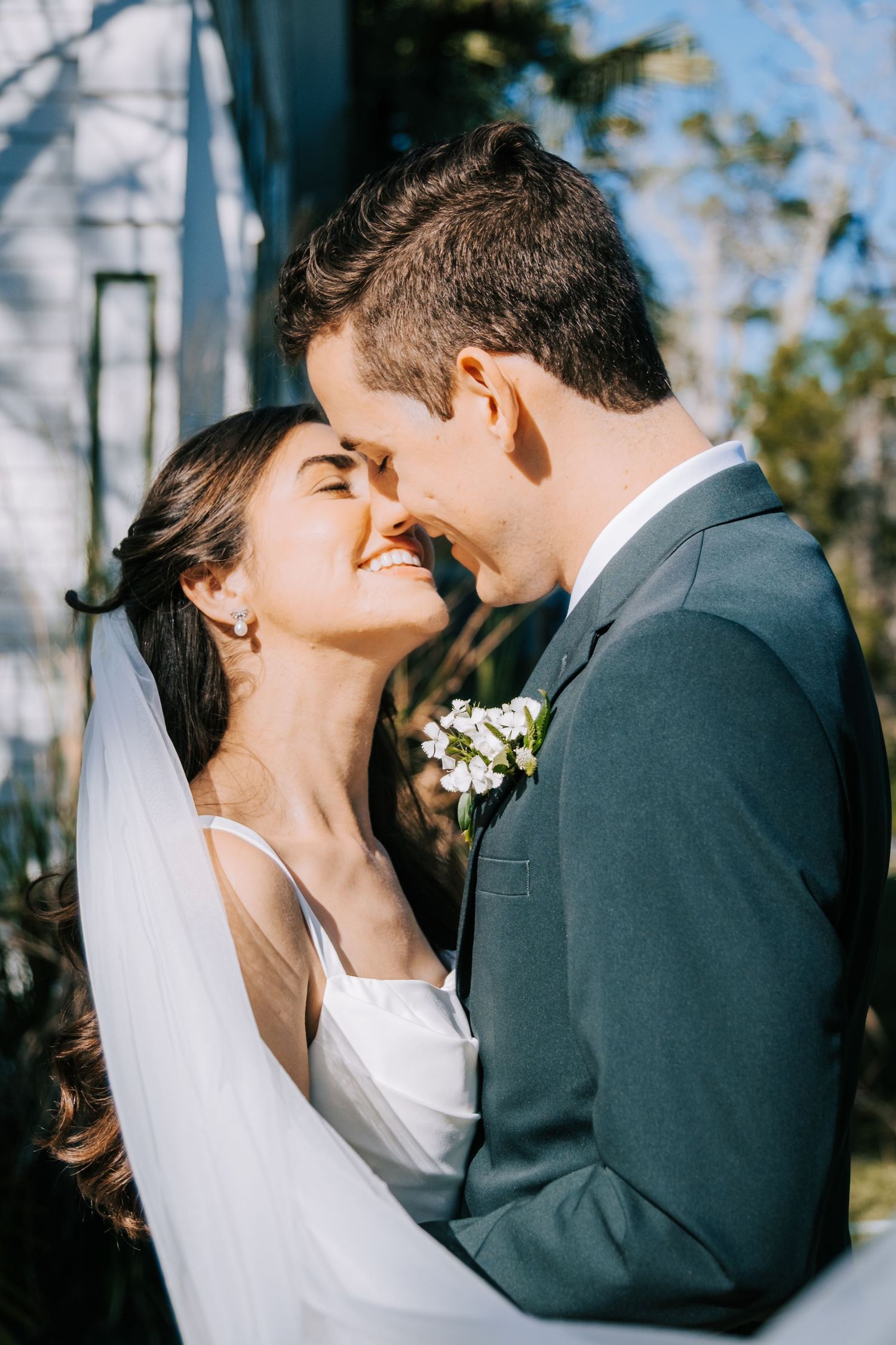 A romantic wedding portrait of a couple sharing an intimate moment outdoors.