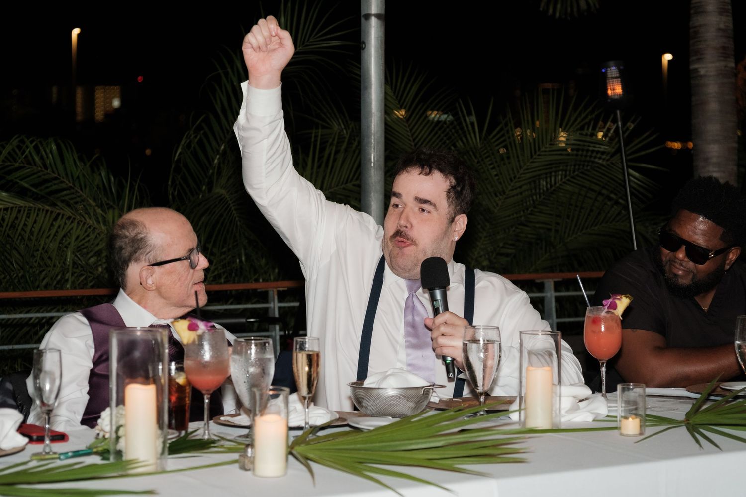Wedding reception guests celebrating at night under outdoor lighting.