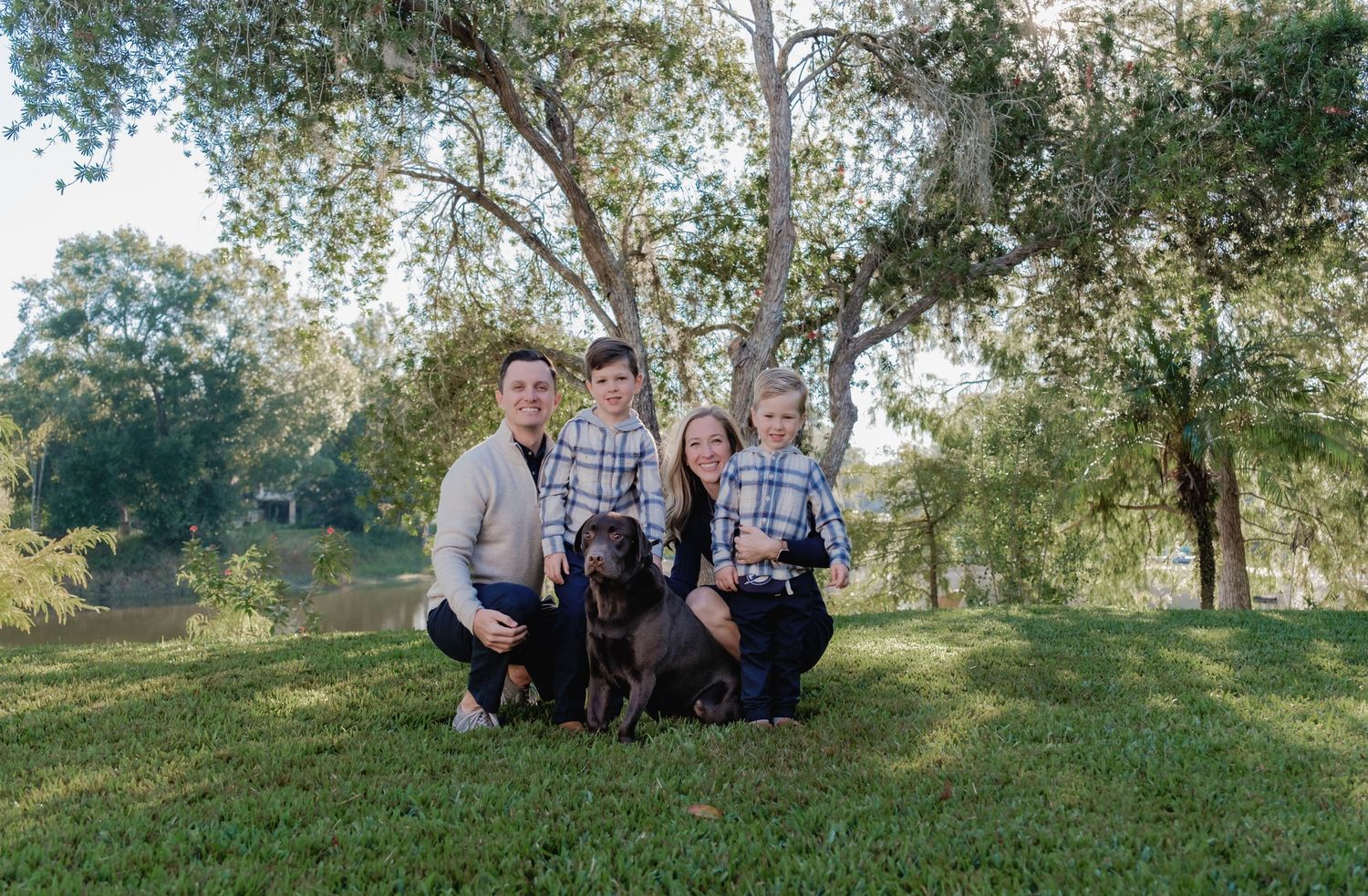 Family group photo taken from a distance on a grassy hillside with trees in the background.