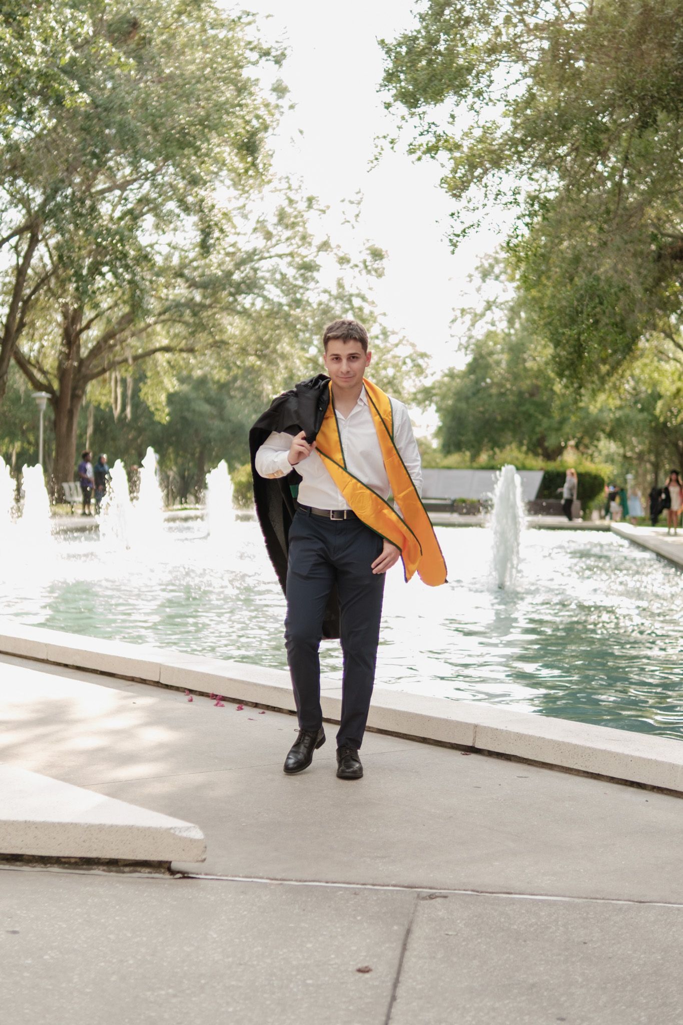 A sequence of four photos showing someone in formal attire walking along a waterfront path on a sunny day.