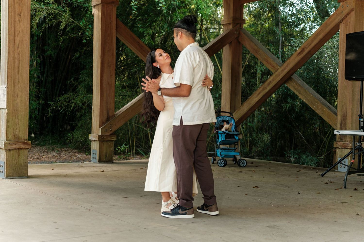 Wedding guests dancing and celebrating under a rustic wooden pavilion structure.
